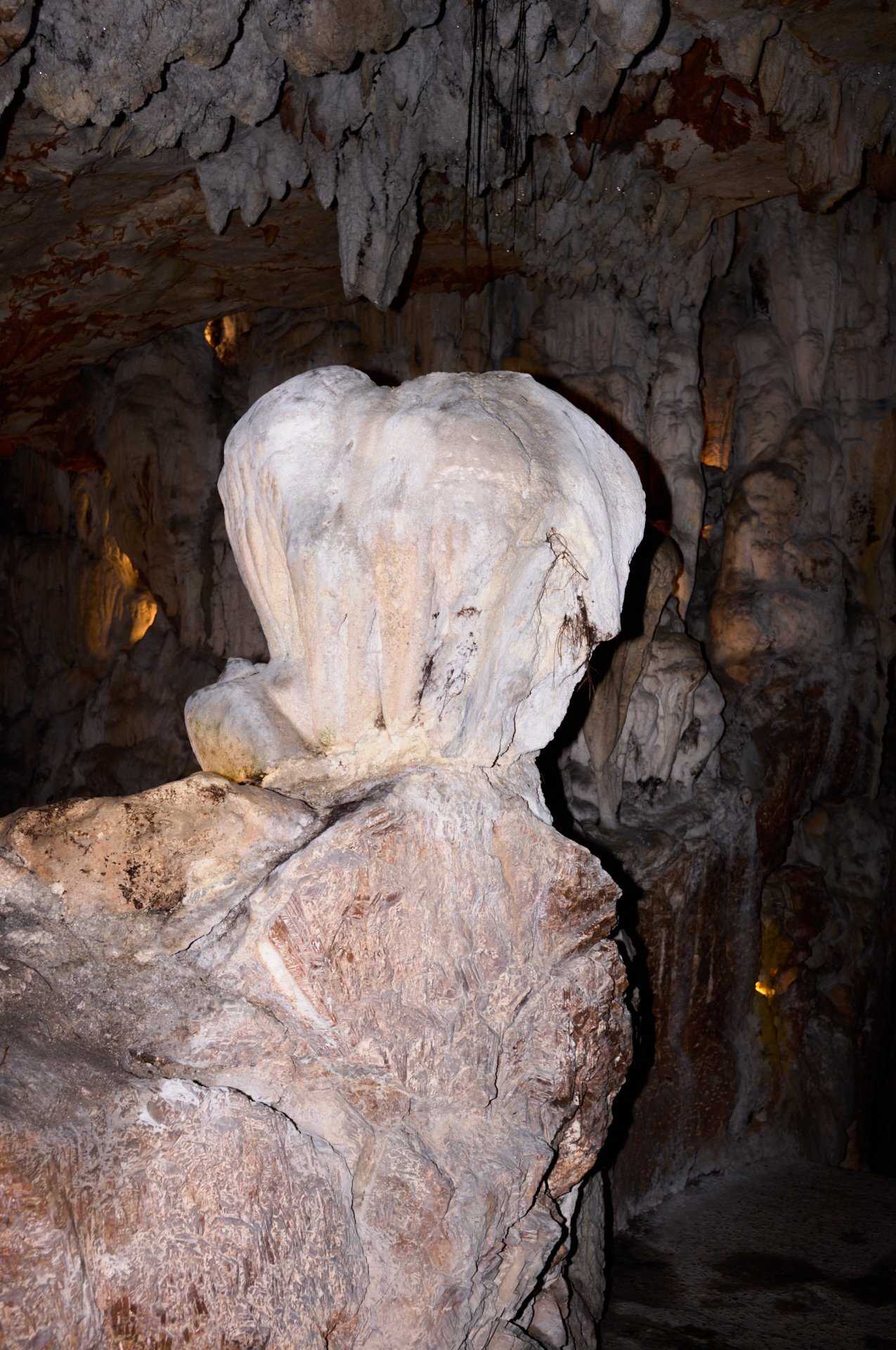 Inside a cave with large rock formations and stalactites hanging from the ceiling.
