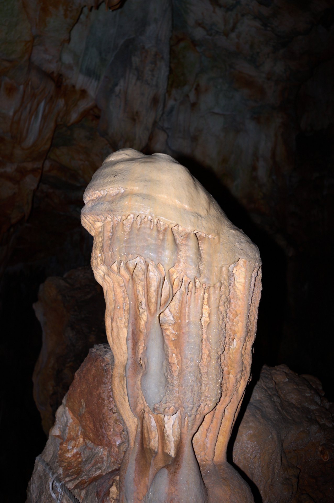 A large stalagmite formation inside a dark cave.