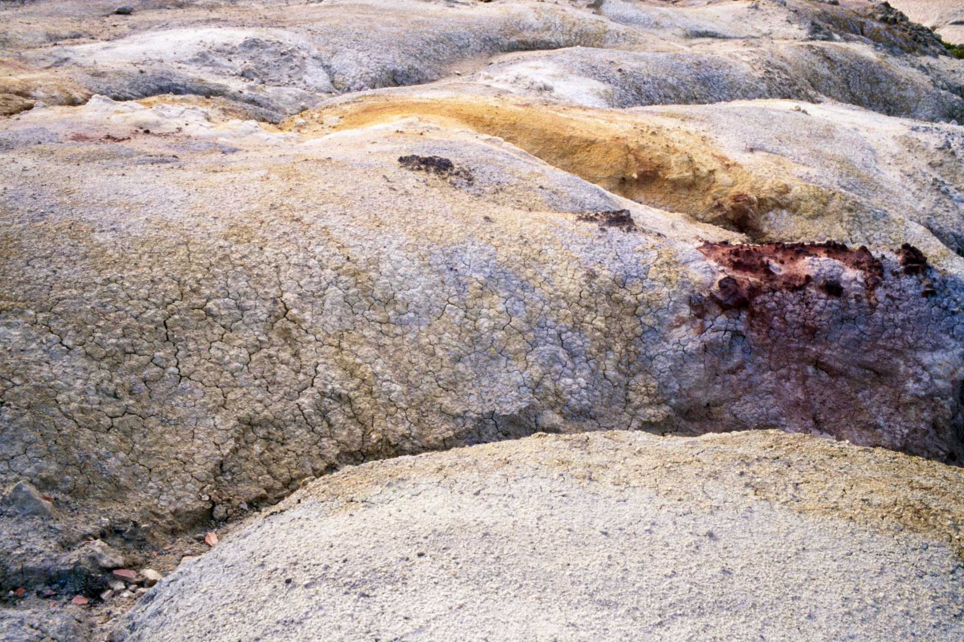Close-up of cracked and weathered dry, desert soil with some rocks.