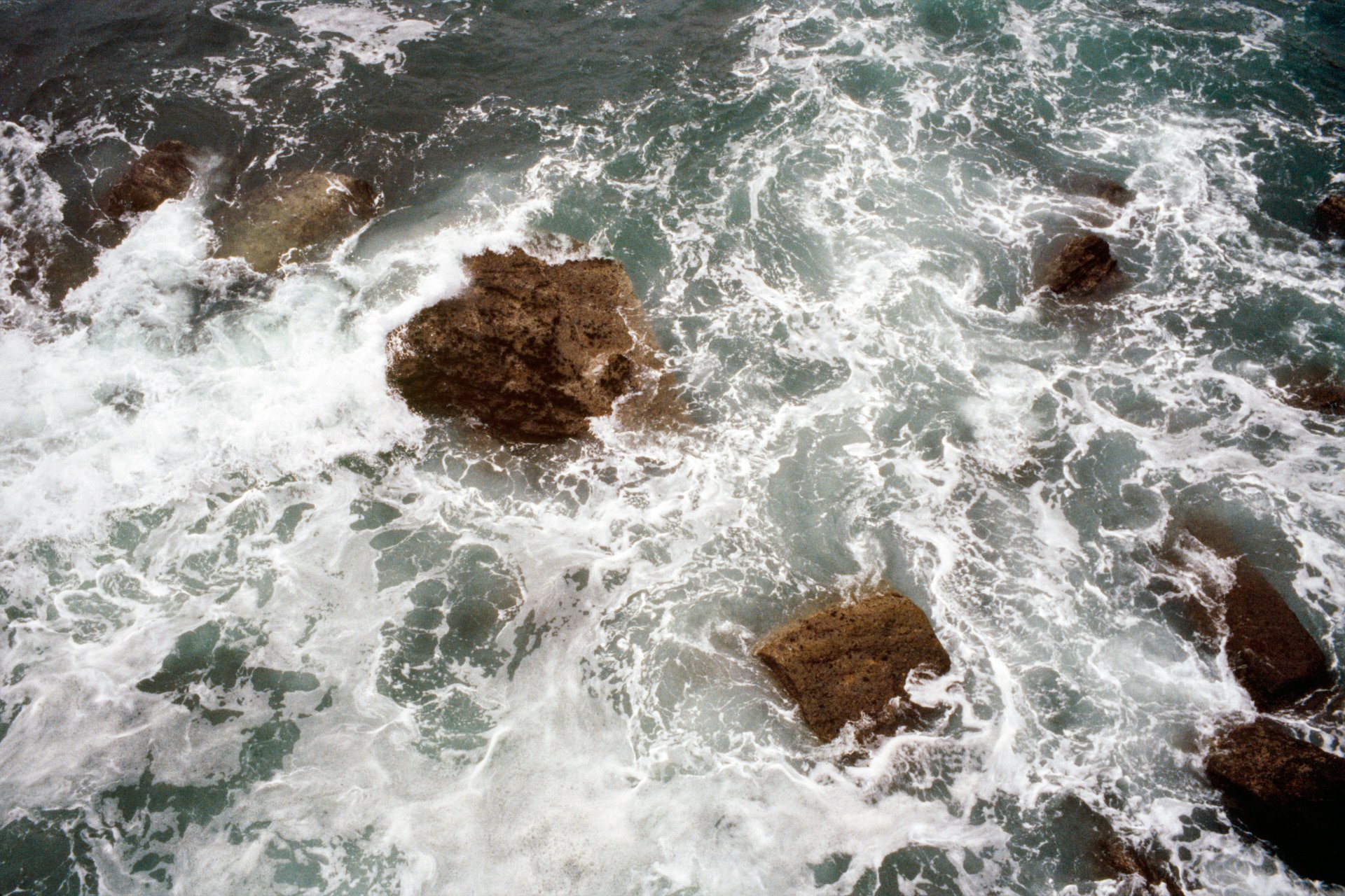 Ocean waves crashing against rocks along a shoreline.