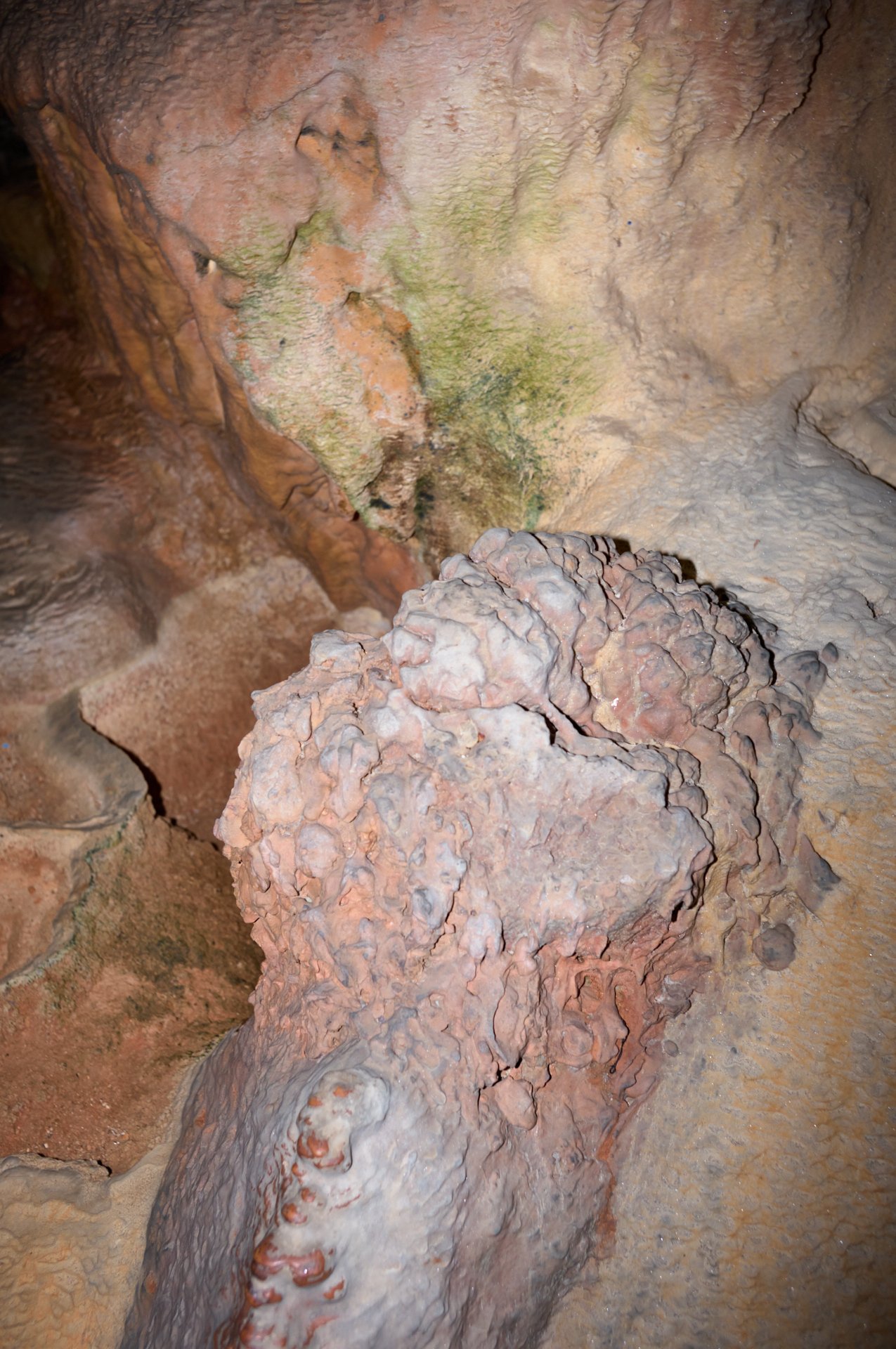 Inside a cave with stalagmites and colorful mineral deposits on the walls.