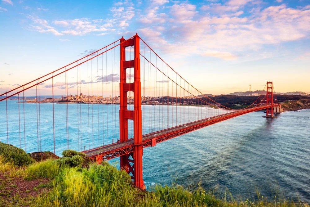 Golden Gate Bridge in San Francisco during sunset with blue water and a city in the background