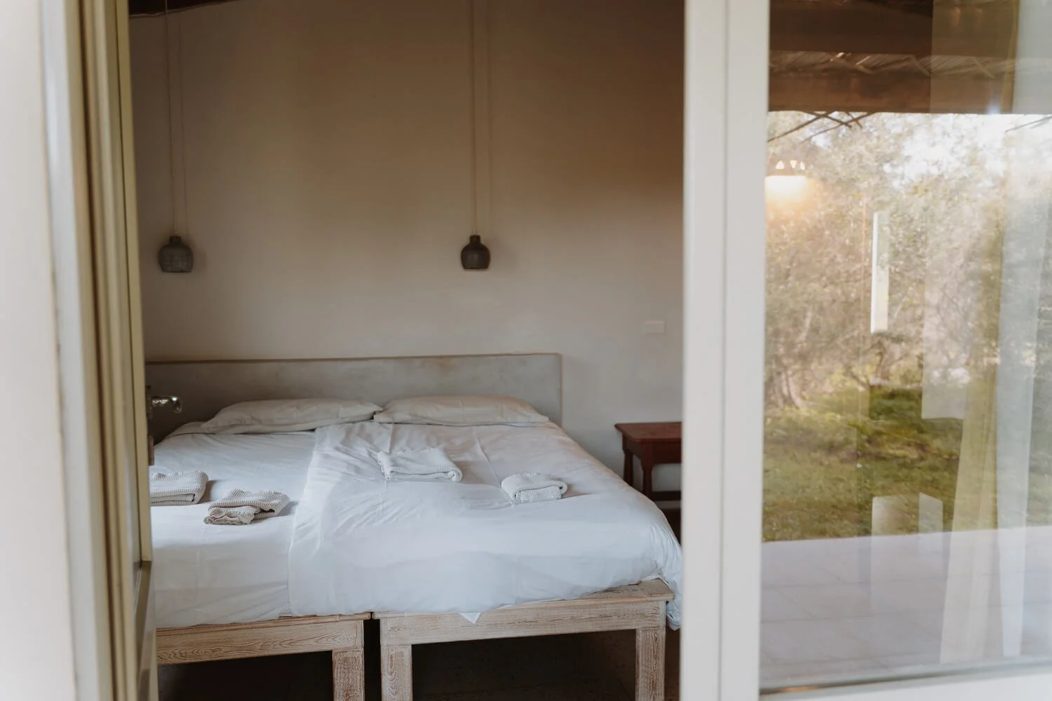 Stanza da letto con ampia finestra sul giardino fiorito del cottage Ginestra