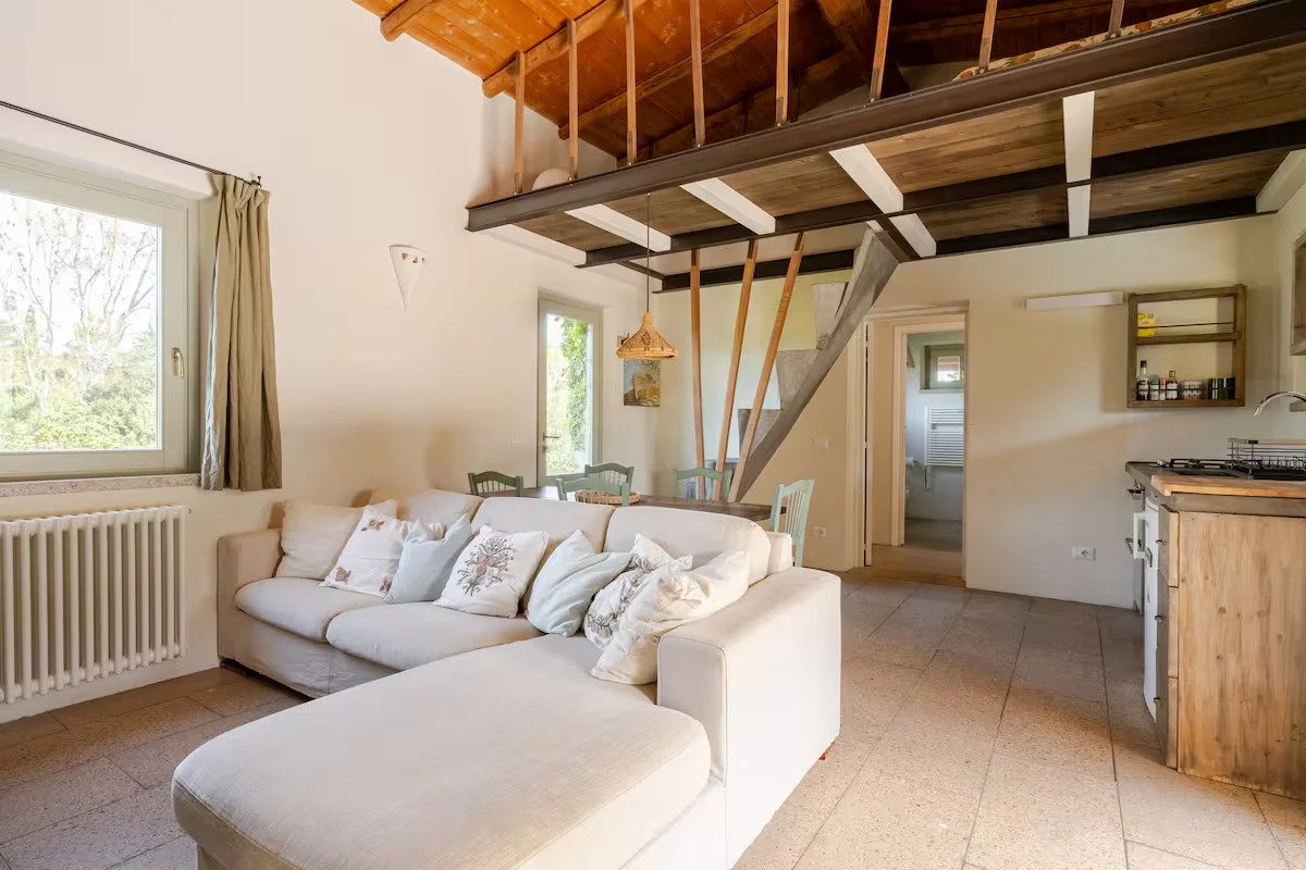 Salotto luminoso e arredato del cottage Ginepro con ampio divano e camino