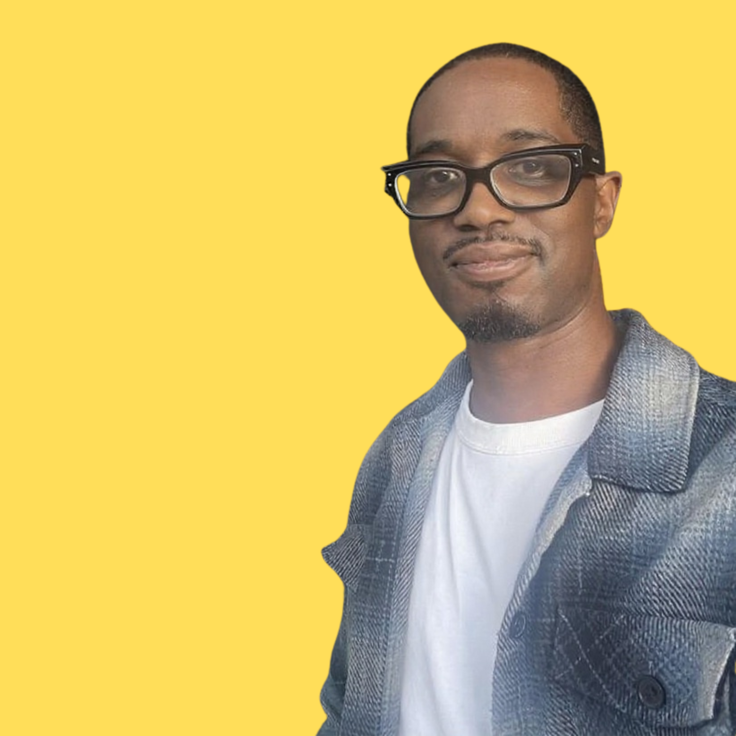 A man with glasses, a goatee, and short hair smiling, wearing a white T-shirt and a denim jacket, against a yellow background.