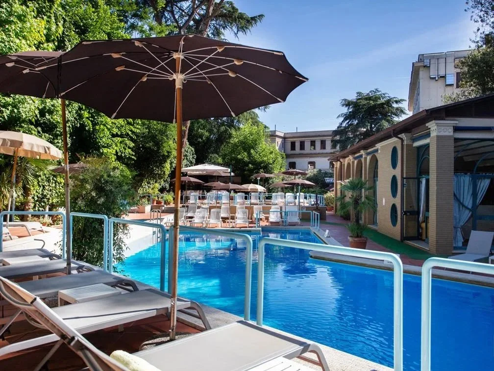 Outdoor garden swimming pool with umbrellas and loungers at Aldrovandi Swimming Pool near Villa Borghese, Rome