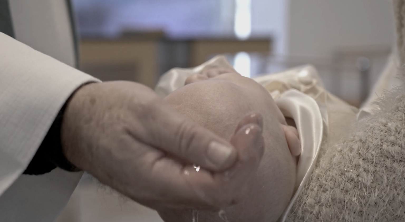 Ein Priester in der Kirche tauft mit gesegnetem Wasser ein Neugeborenes.