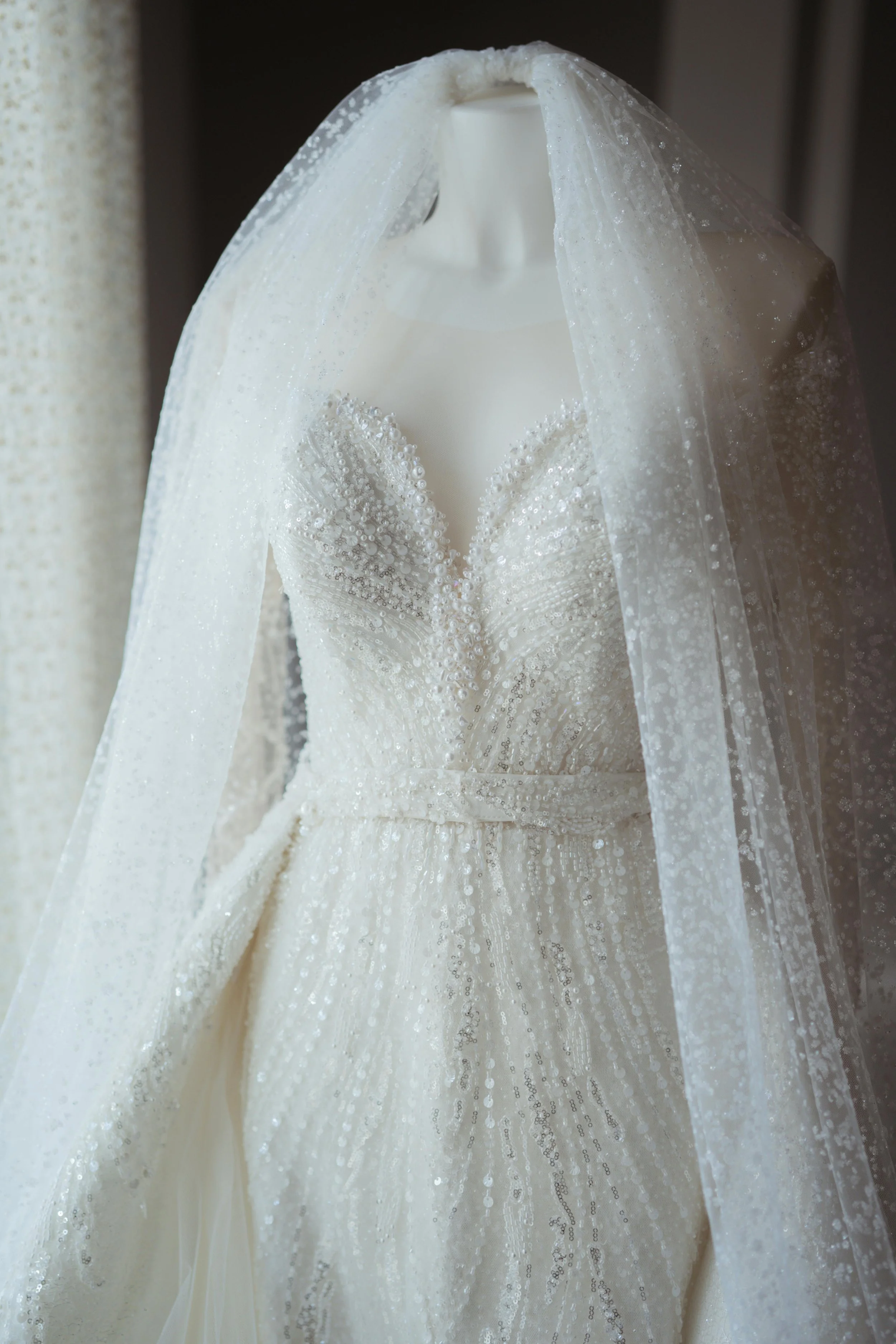 Weiße Brautkleid mit Perlen und Tüll, auf einem Stehkopf-Hänger, im Nahaufnahme.