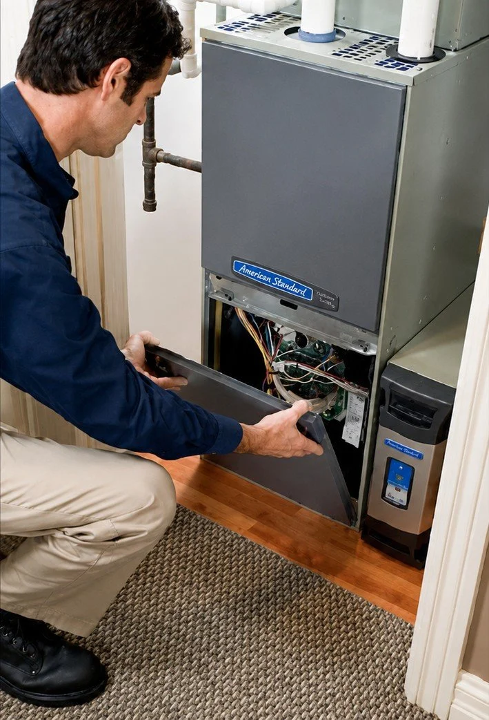 HVAC technician performing preventative furnace maintenance and inspection on a residential heating system.