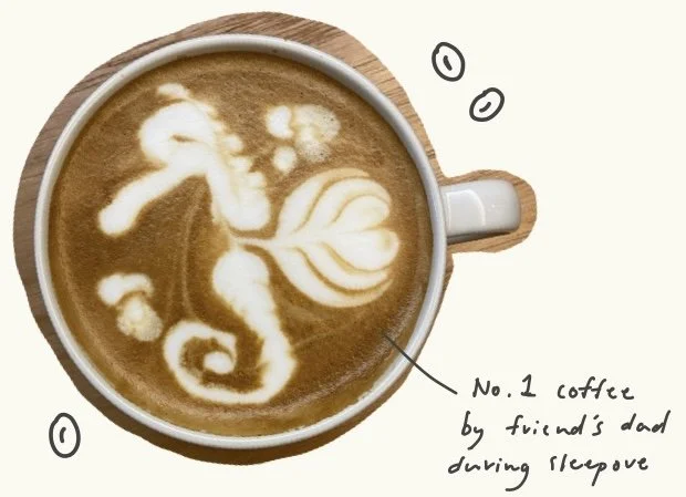 A cup of coffee with a seahorse design in foam, surrounded by handwritten annotations and small doodles.