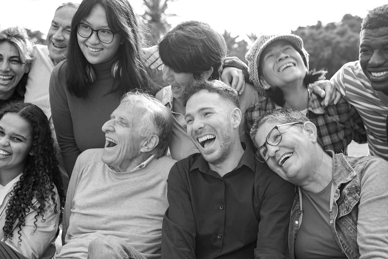 A diverse group of people smiling and laughing together outdoors.