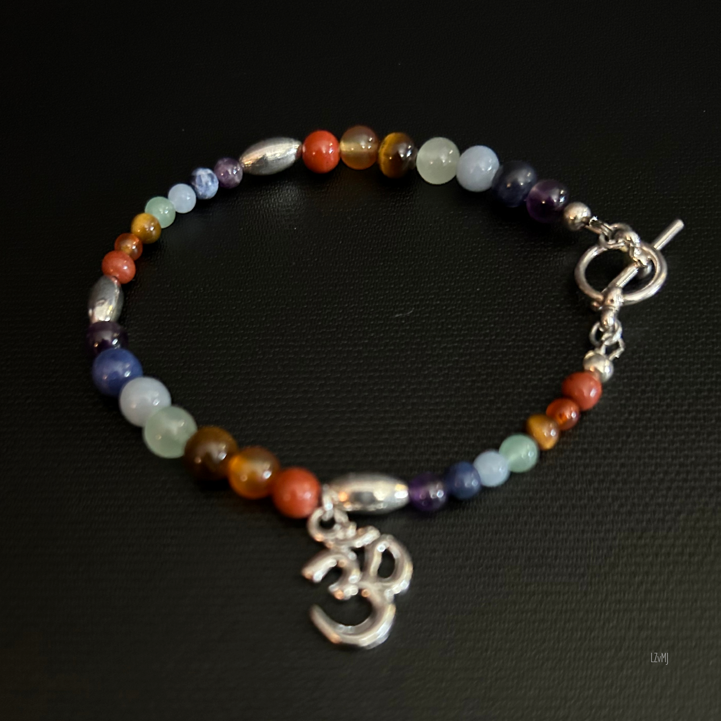 Detail of the chakra‑color stones with the silver Om charm