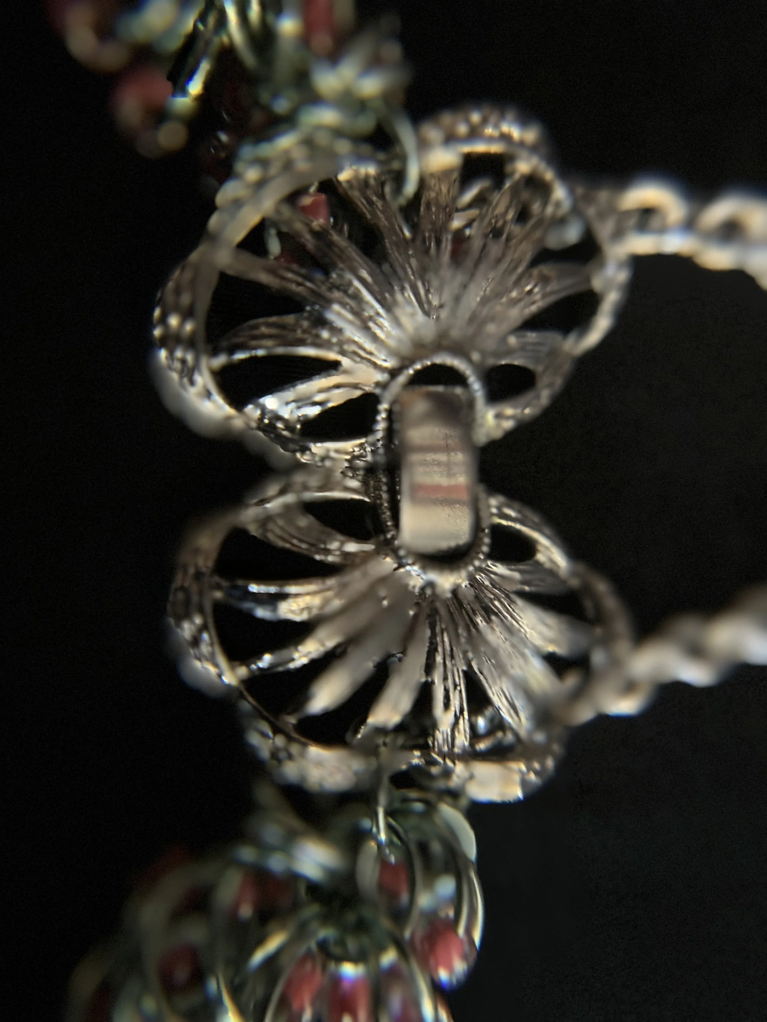 Chainmaille bracelet clasp shown in close‑up, featuring a silver‑plated butterfly design with pink and green bead accents and green‑tinged silver rings.