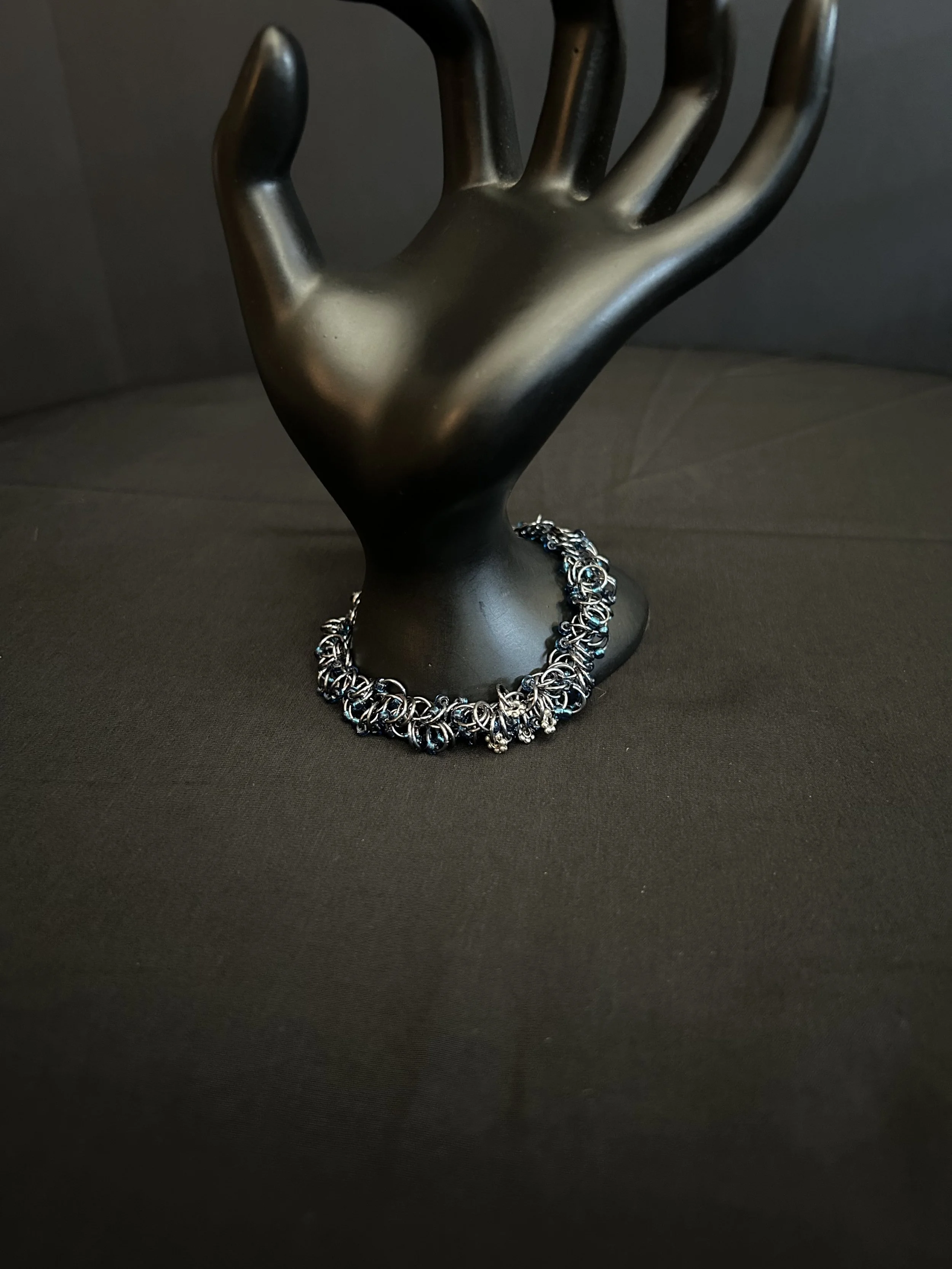 Midnight River bracelet draped over a neutral prop, showing the movement of the shaggy‑loop weave and deep blue accents