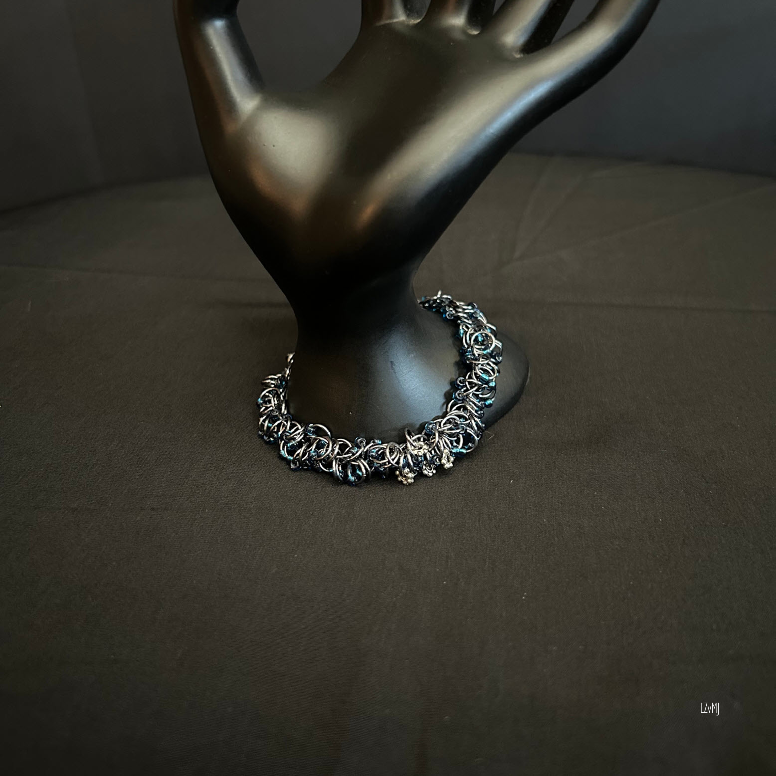 “Midnight River bracelet draped over a display prop showing Black Ice rings and blue beads.”