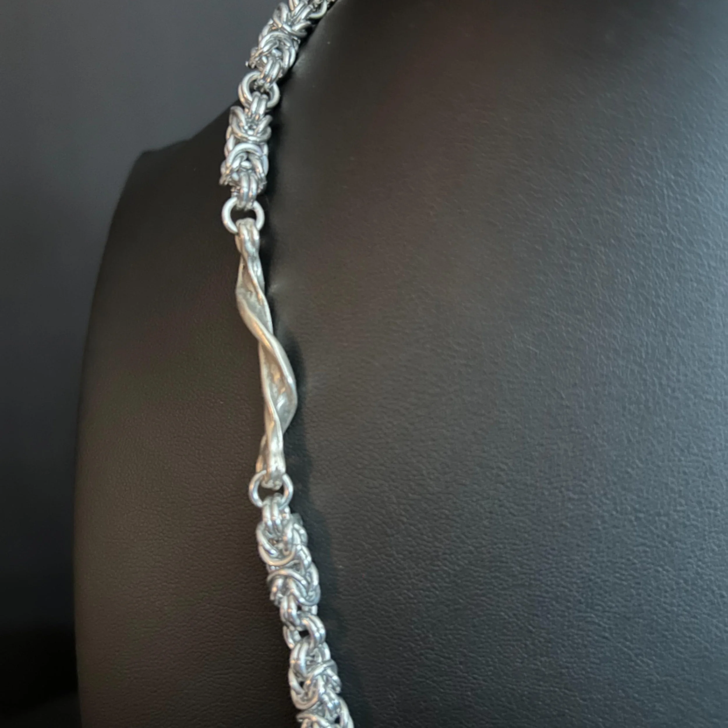 Close-up of the Silver Forest necklace showing the interwoven chain and central twisted silver segment