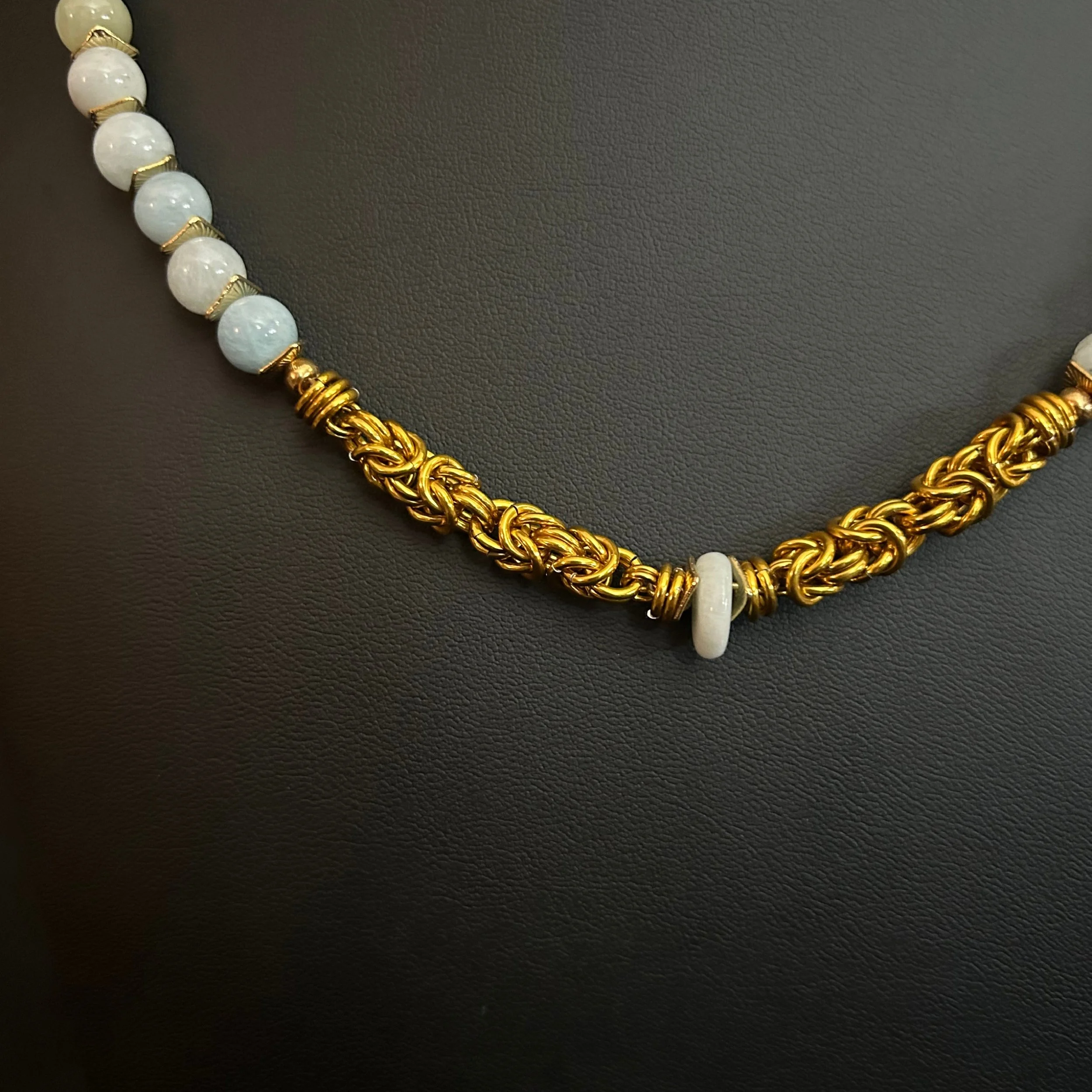 “Close-up of the aquamarine focal with gold‑tone spacers and aluminum chain weave.”