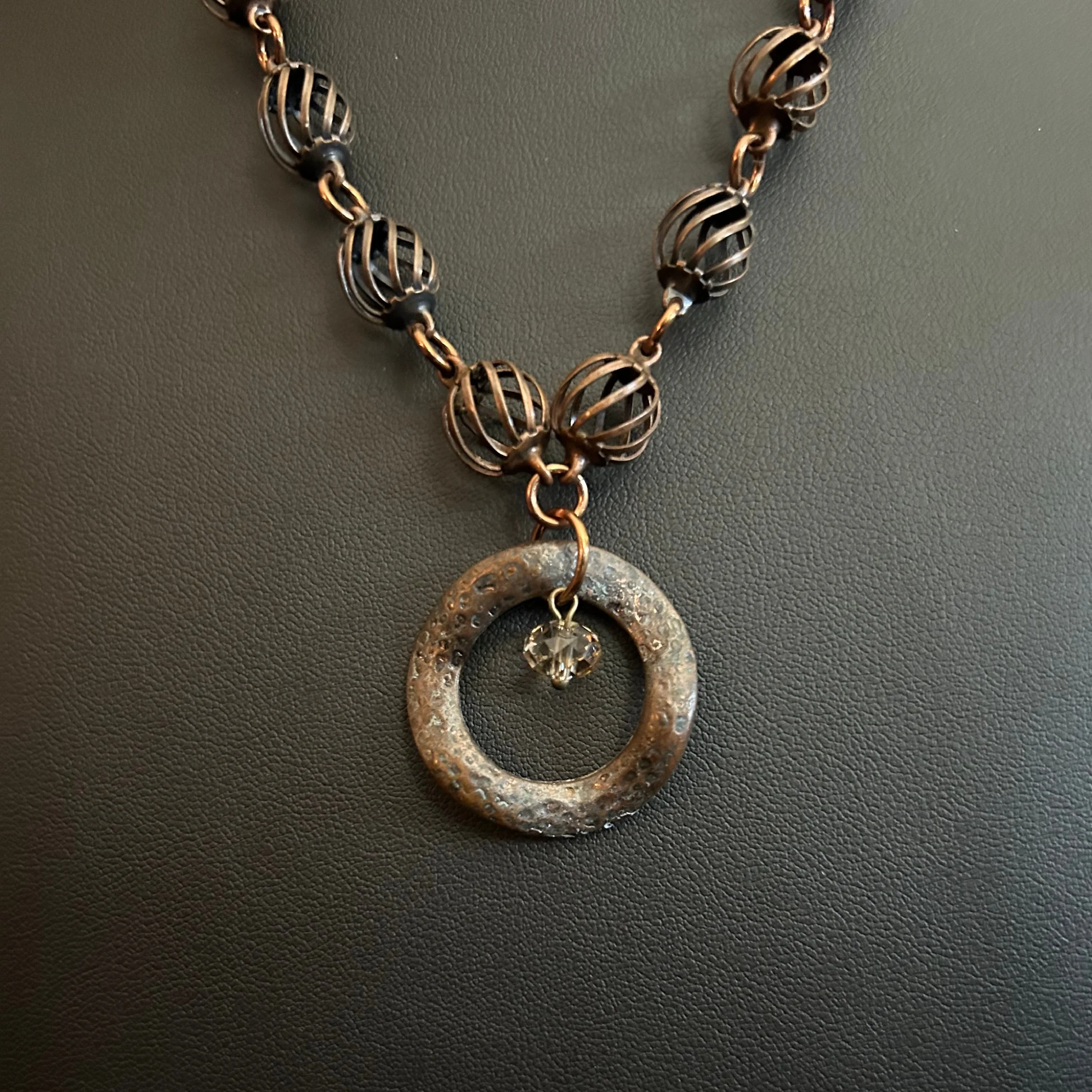 “Close-up of the bronze focal ring with suspended crystal bead.”