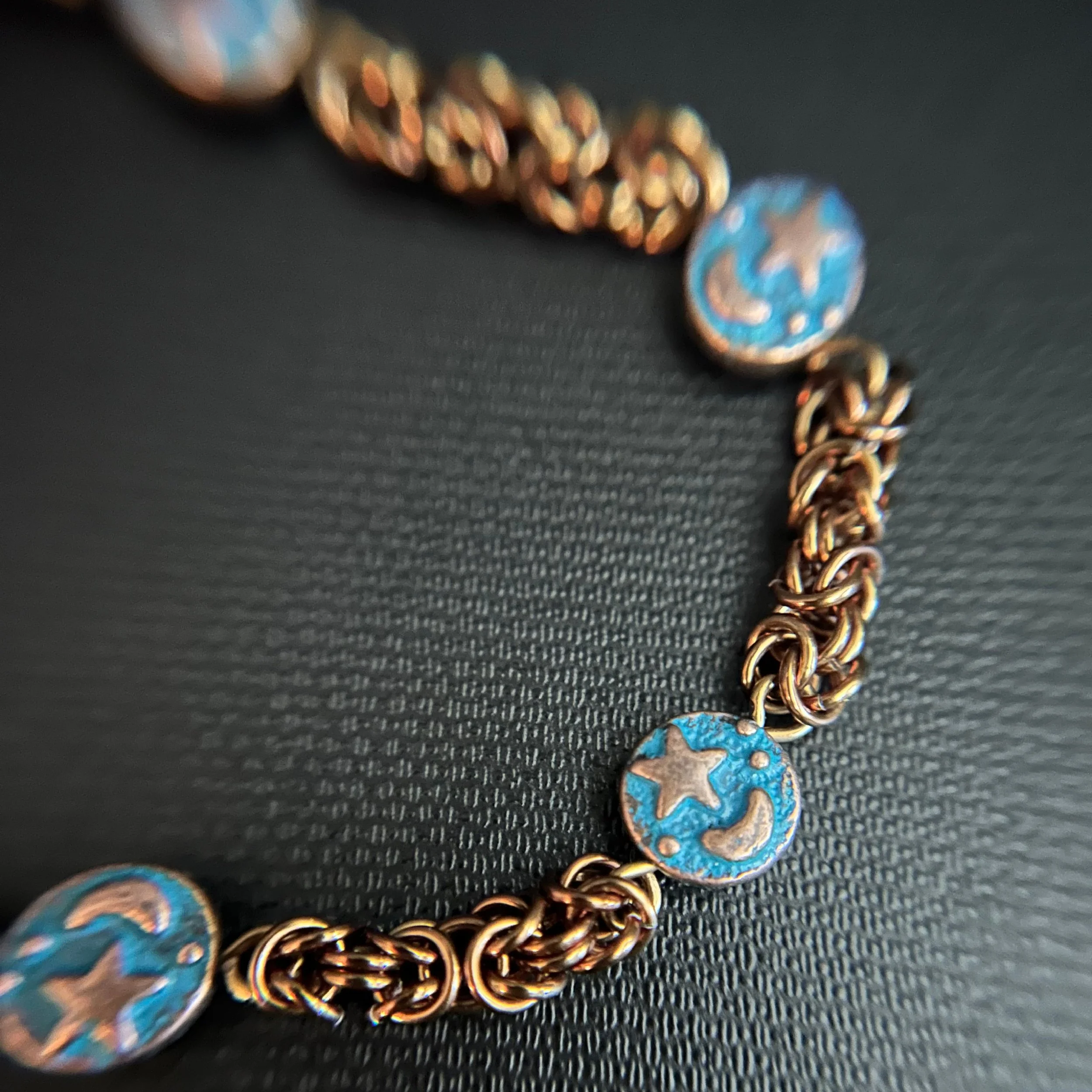 Detail of the blue enamel charm with star and moon design set among bronze chain rings