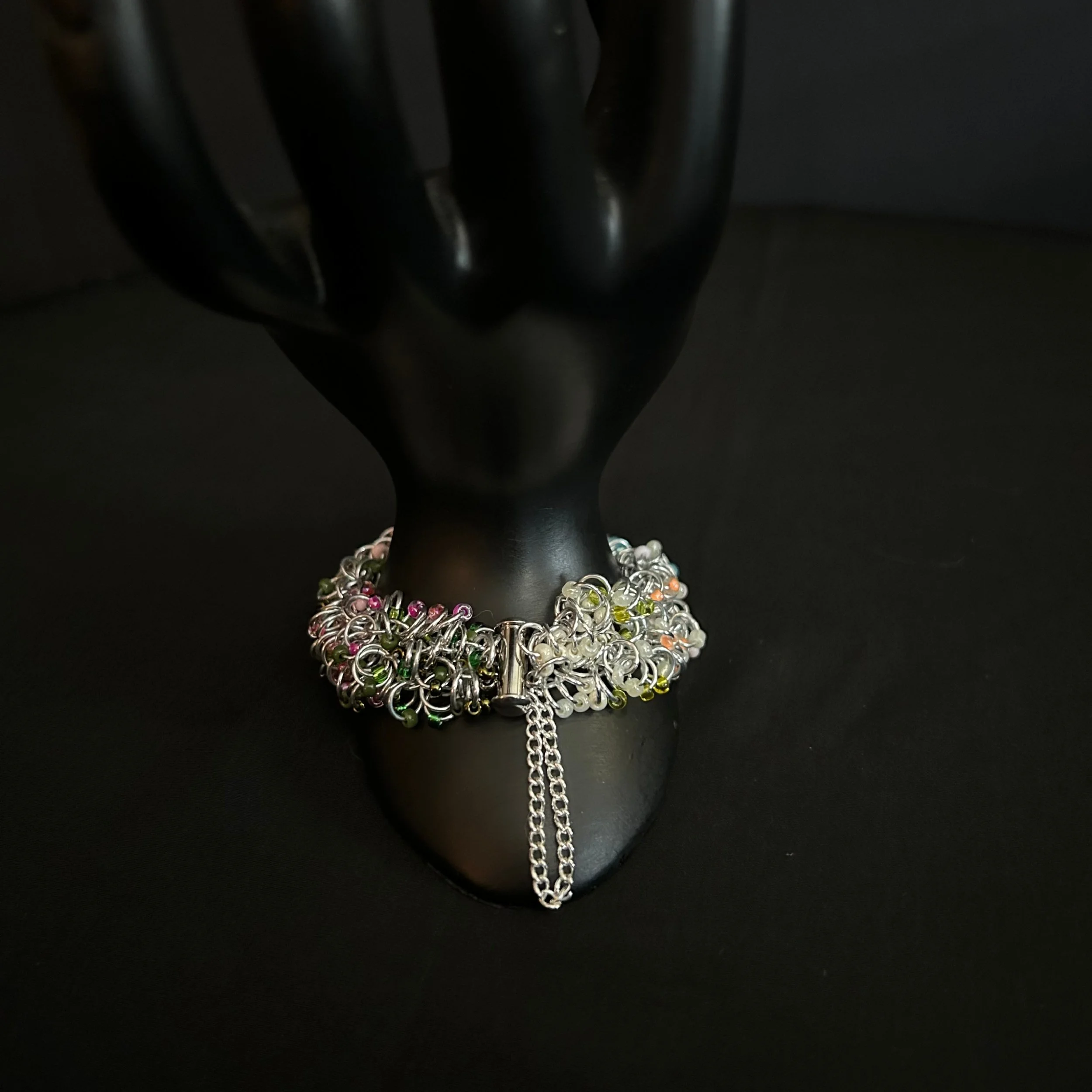 “Bracelet on display prop with the slide‑lock clasp and safety chain visible.”