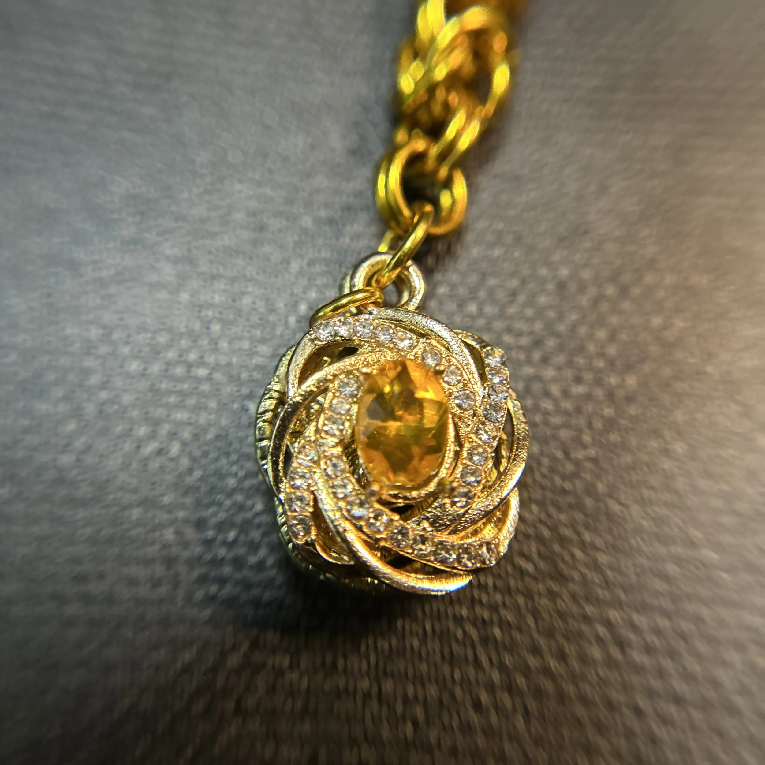 Closeup of the clear pave and gold crystal focal on a gold‑tone Byzantine chainmaille purse charm.