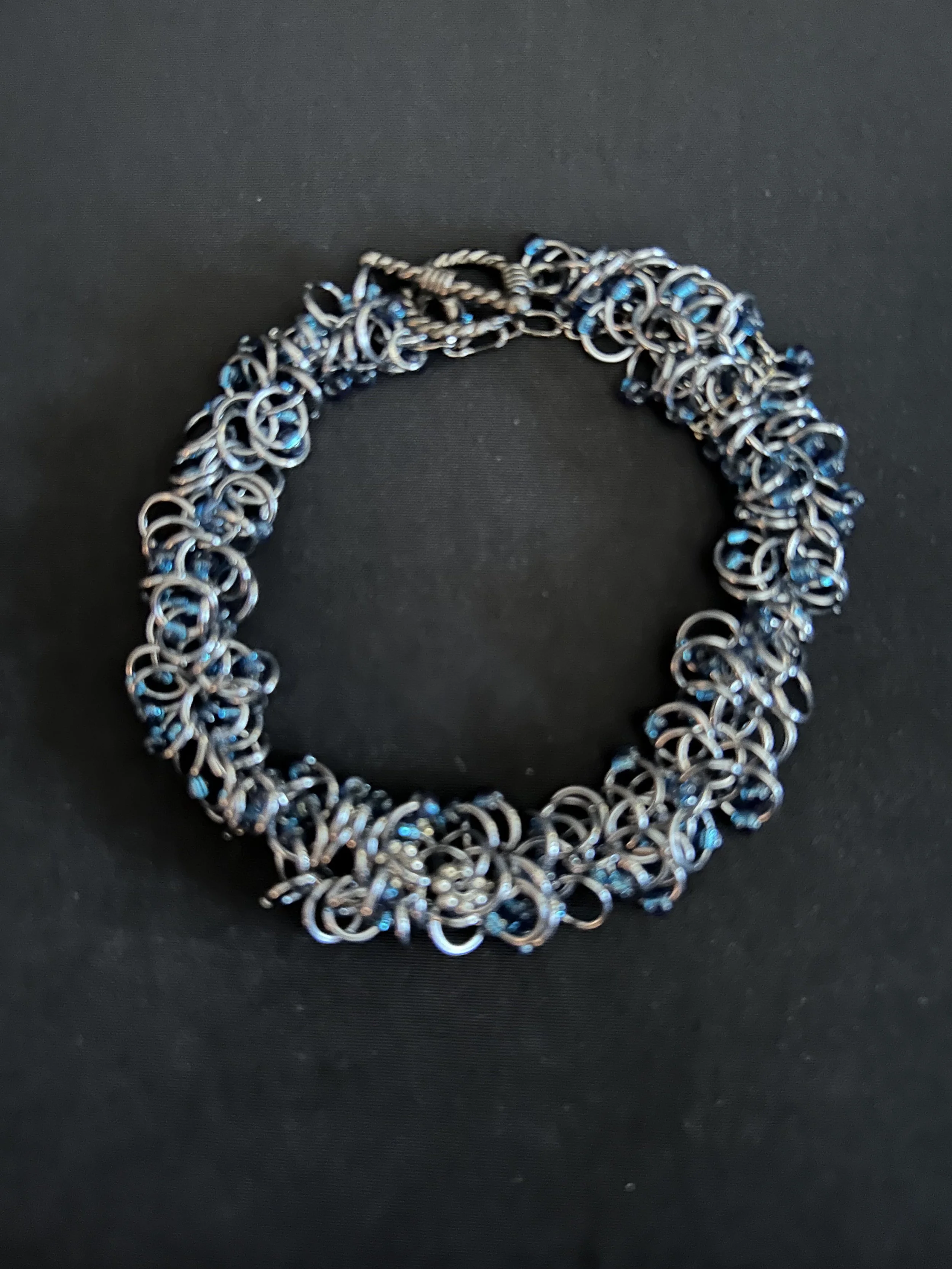 Midnight River bracelet shown laid flat on a light background, highlighting the Black Ice rings and midnight blue beads