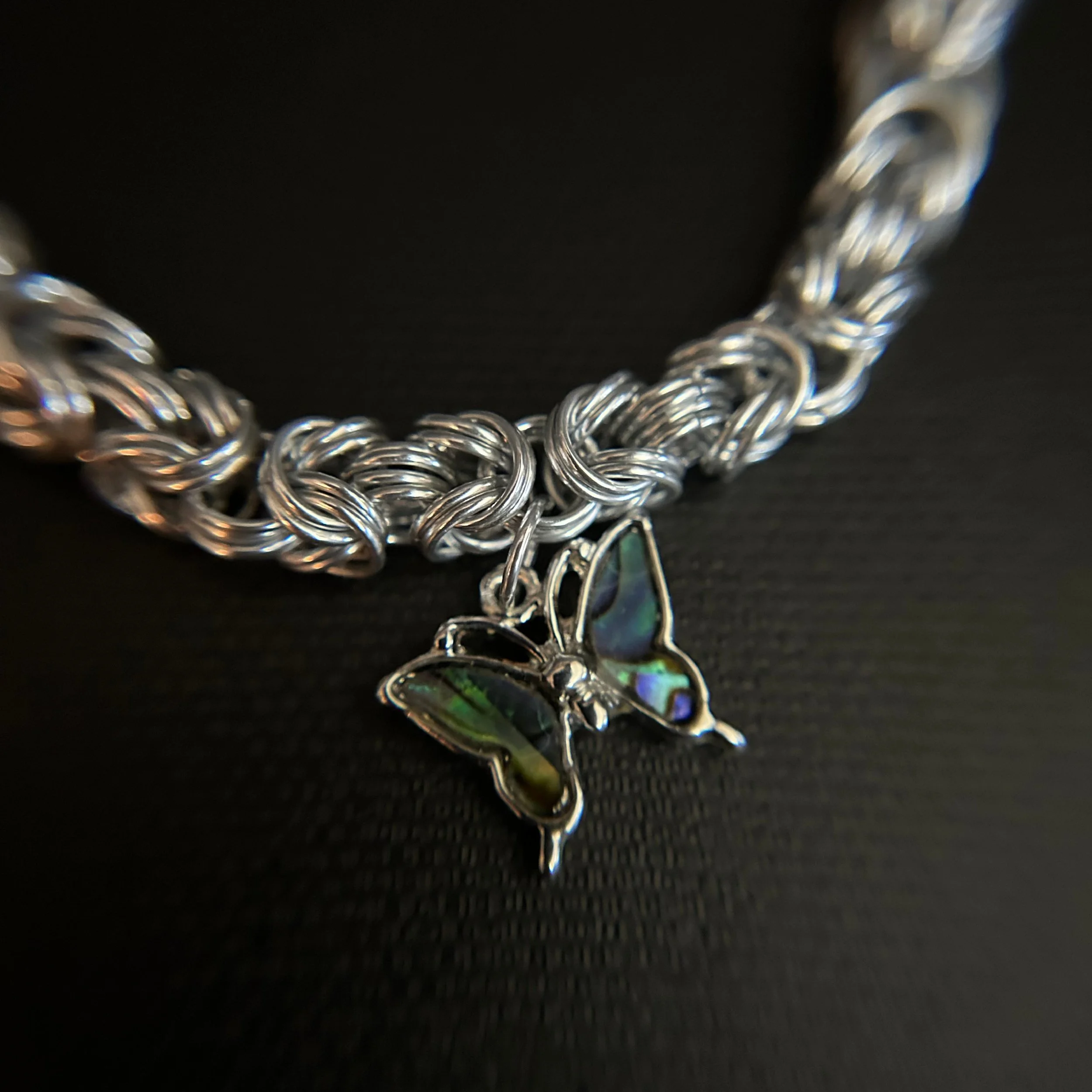 “Close-up of the paua shell butterfly charm with iridescent color.”