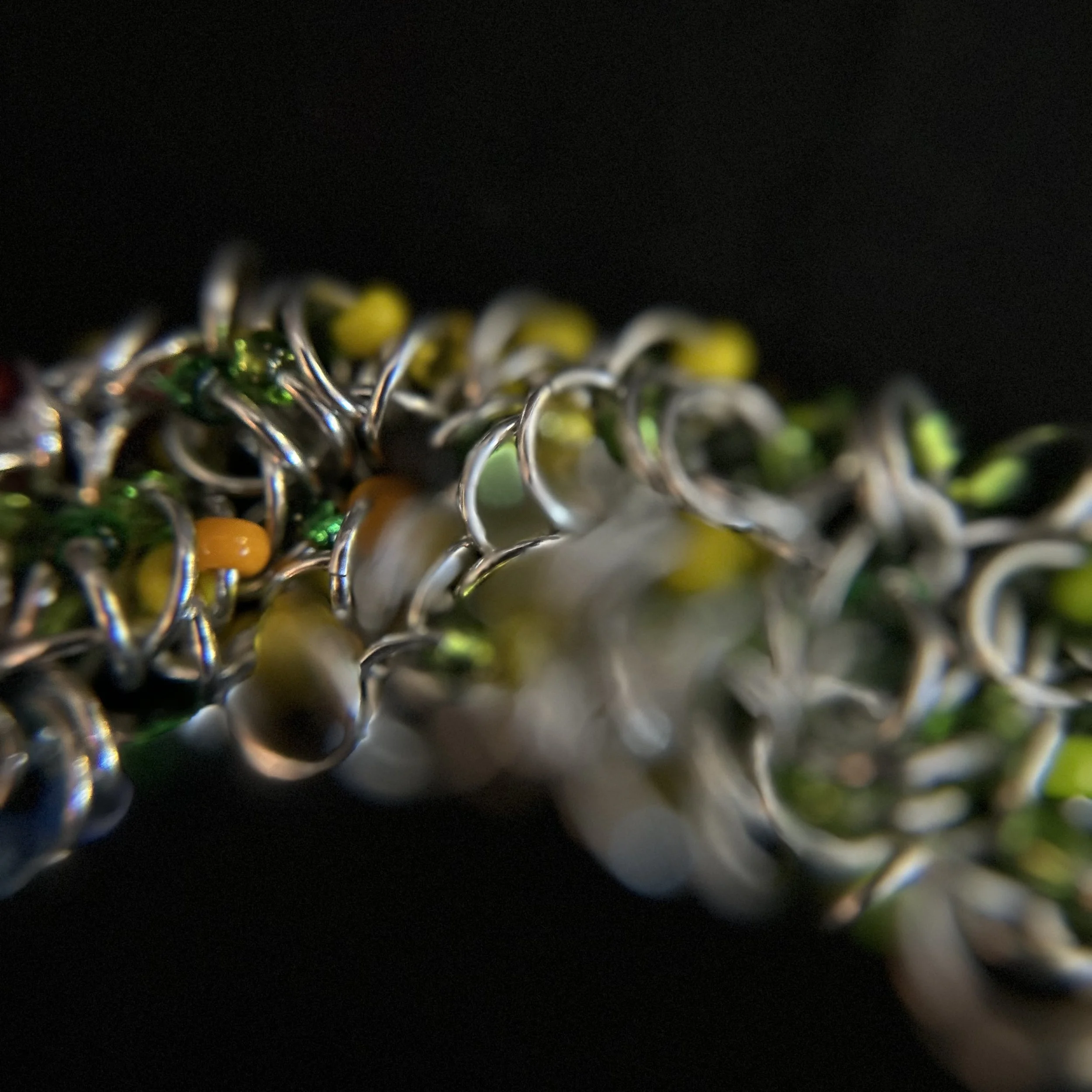 “Detail of the aluminum rings with blue, red, yellow, and green Miyuki beads.”