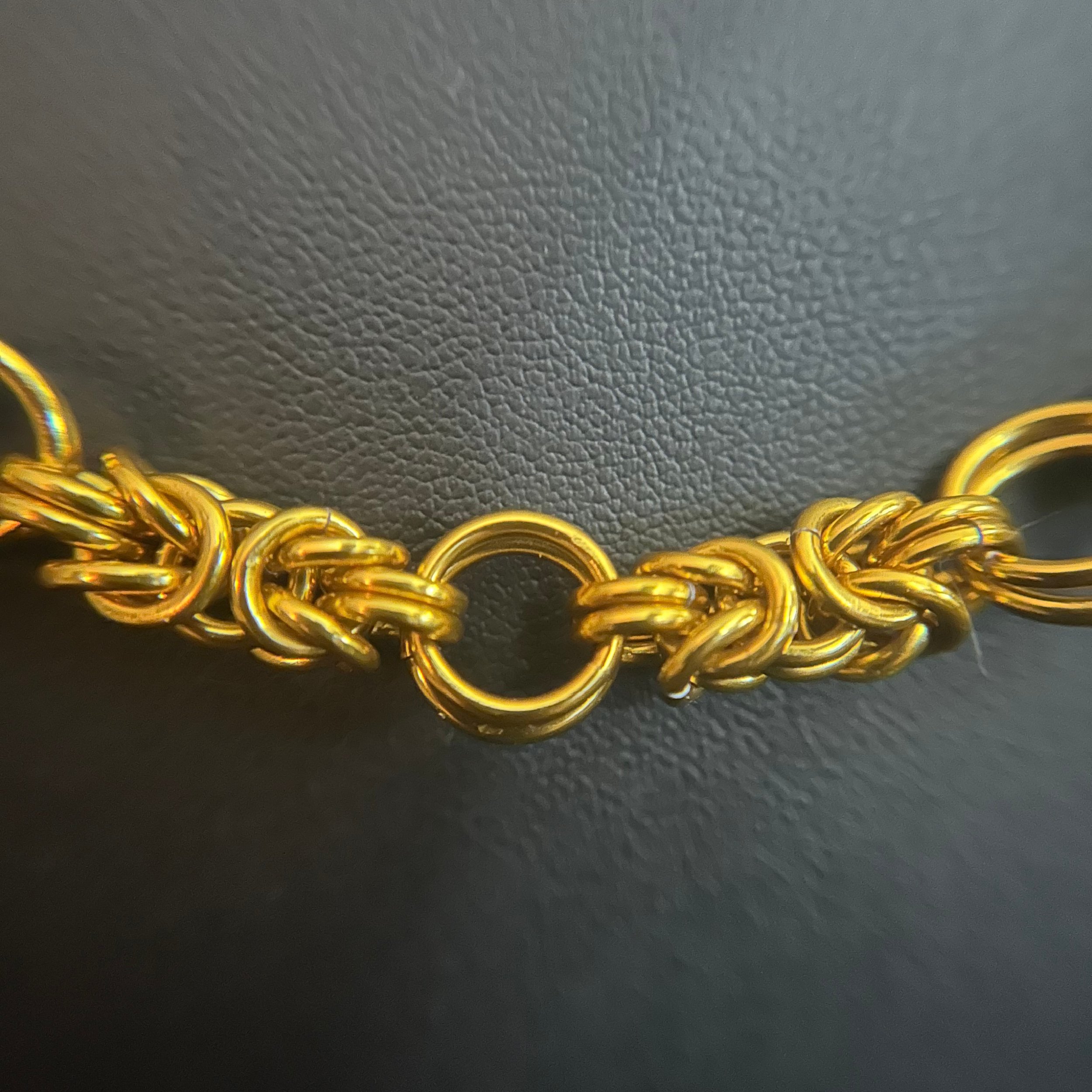 “Detail of the gold‑tone aluminum chainmaille weave.”