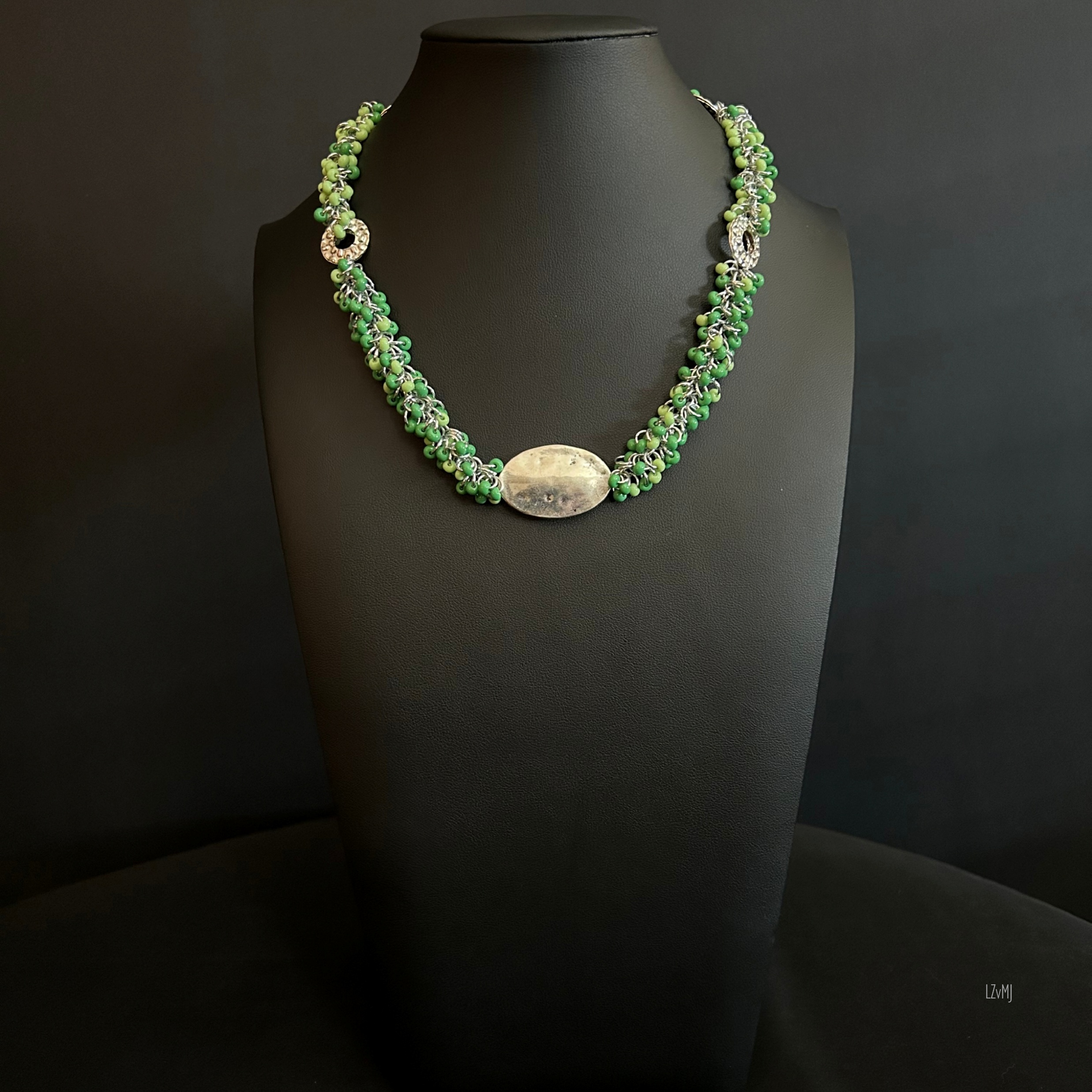“Full view of the Green Renewal necklace with green beads, hammered silver circles, and silver chain.”