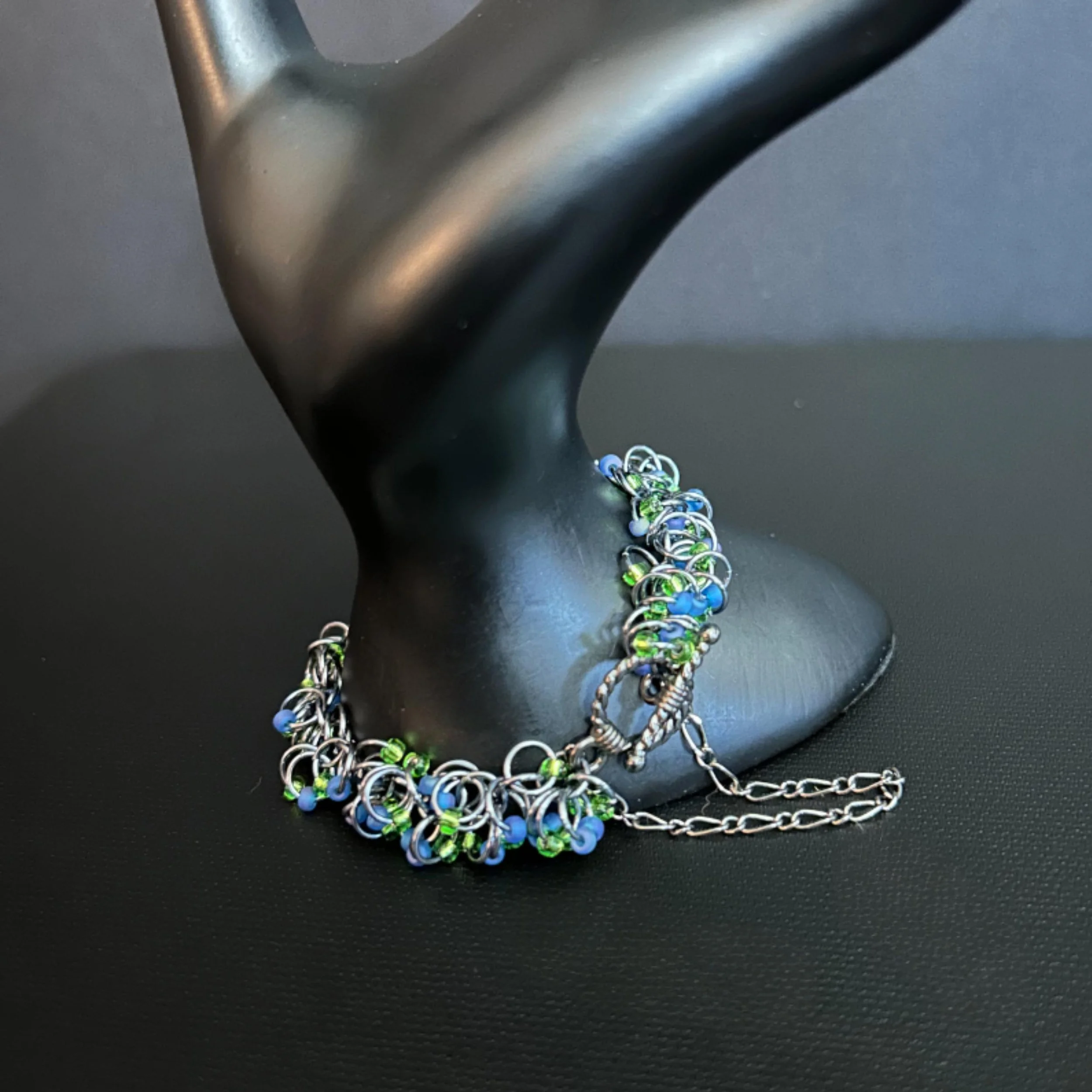 “Close-up of the gunmetal toggle clasp and safety chain on the Riverglint bracelet.”