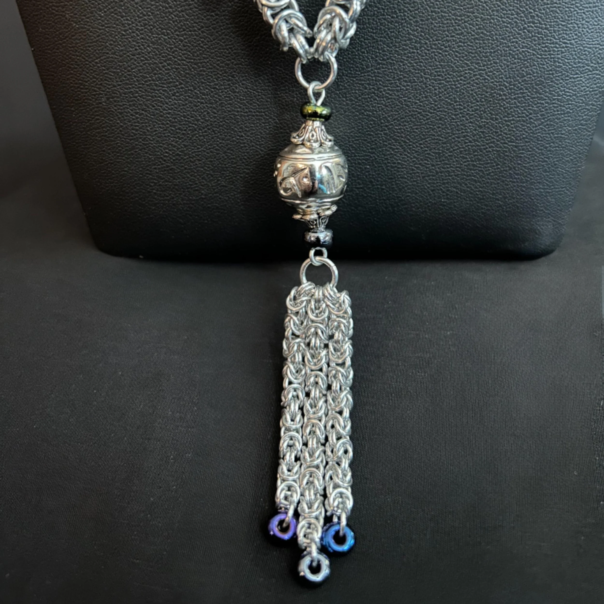 Midnight Tassel bracelet detail with silver chainmaille, dark beads, and a textured toggle clasp on a black display