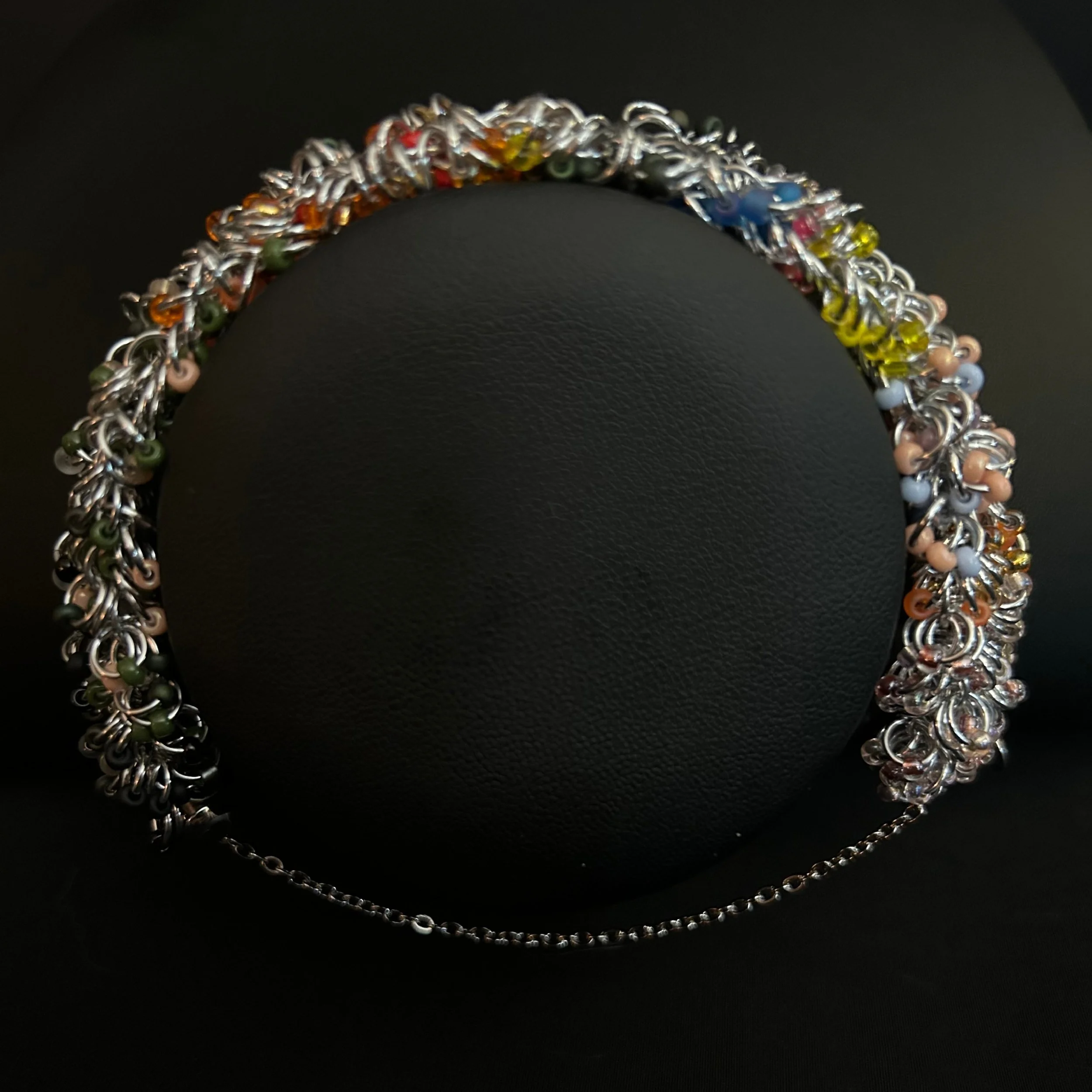 “Autumn‑tone chainmaille bracelet displayed on a black jewelry bust.”