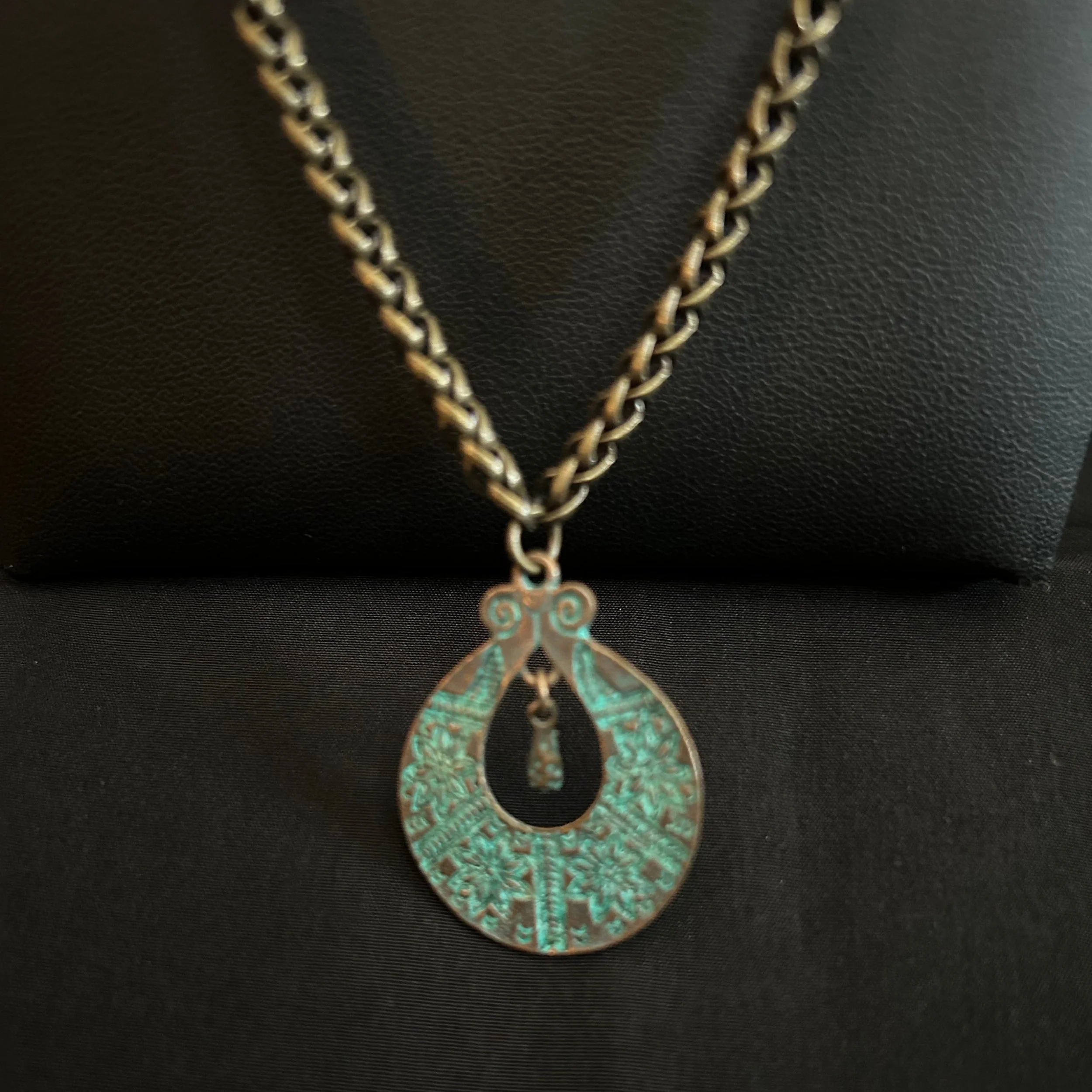 “Close-up of the patina focal ring with suspended bead detail.”