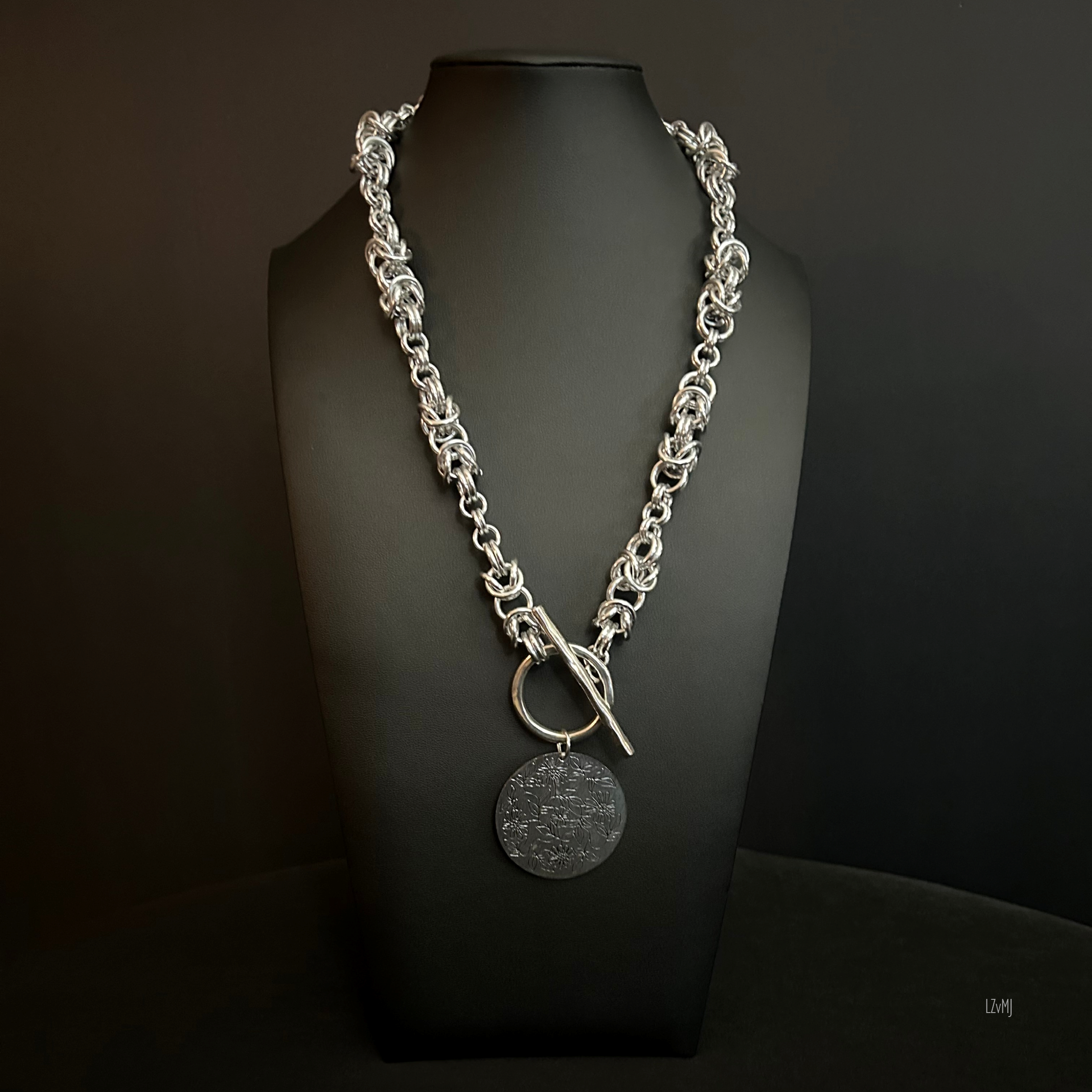 “Full view of the aluminum chain necklace with silver floral focal and front toggle clasp.”