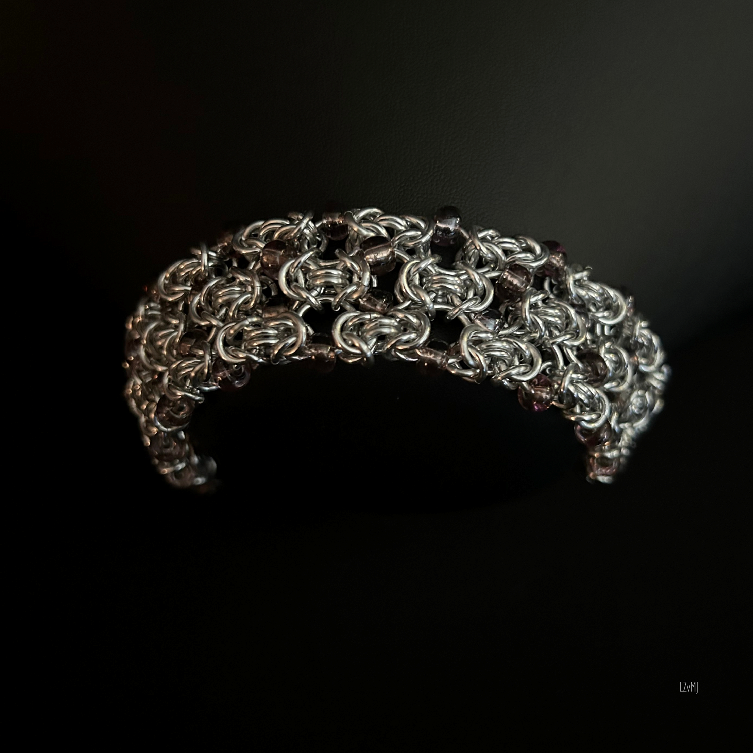 Close-up of the Silverberry Byzantine bracelet showing the interwoven aluminum rings and transparent pale purple glass beads