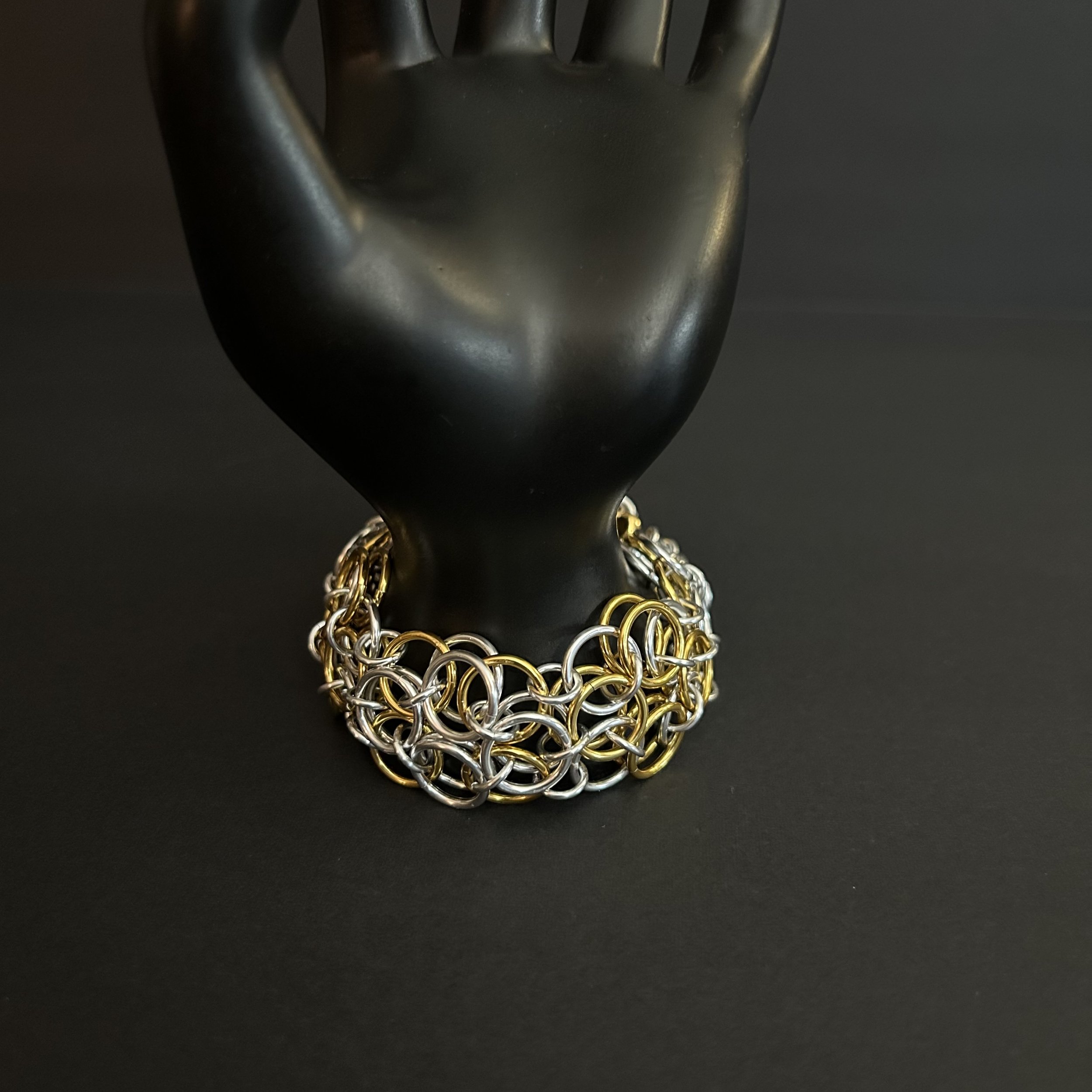 Chainmaille bracelet in sliver- and gold-tone helm rosette weave  on hand prop