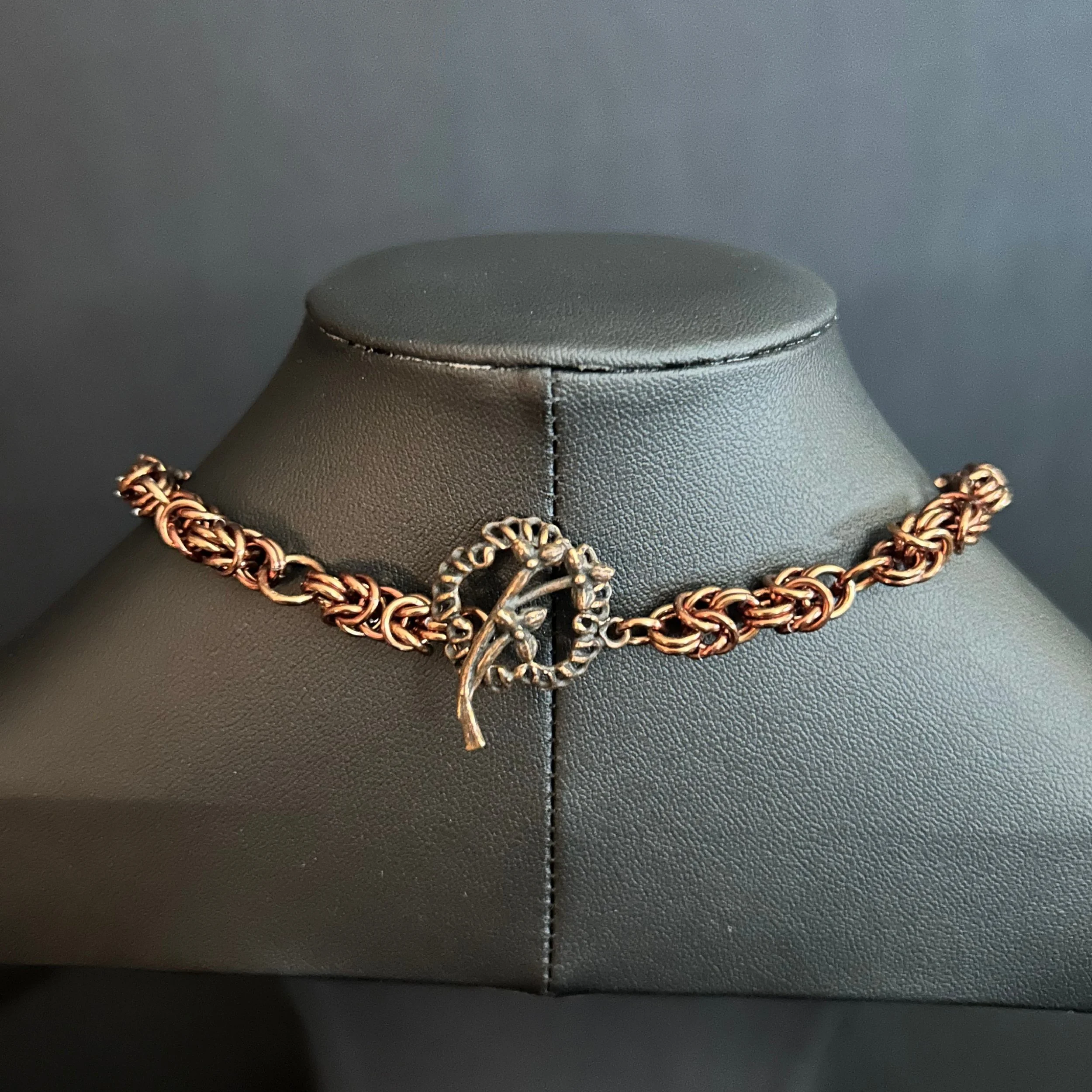 Close-up of the handcrafted bronze toggle clasp and connecting rings.”