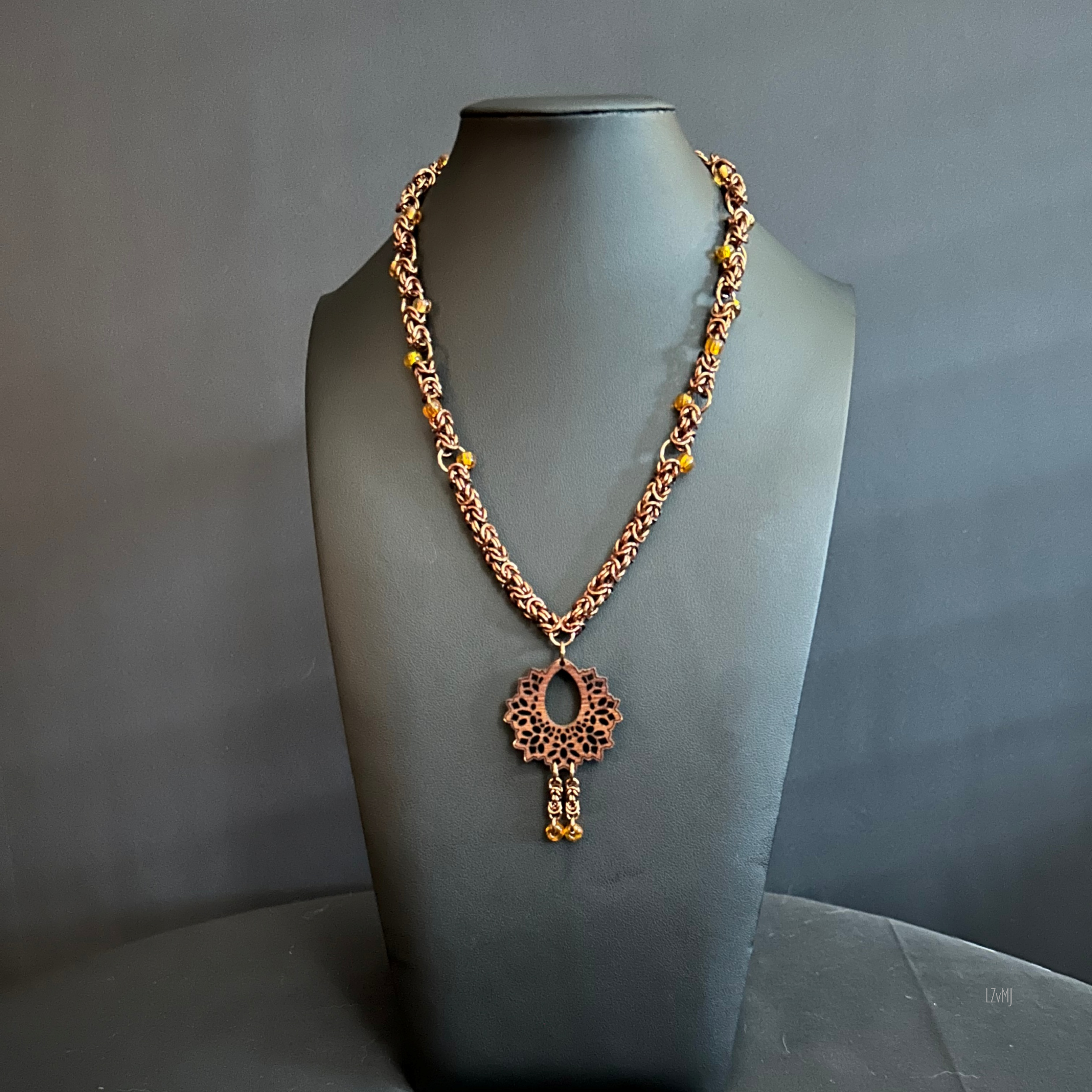 “Full view of the Woodland Lantern necklace with bronze rings, wood focal, and tassel.”