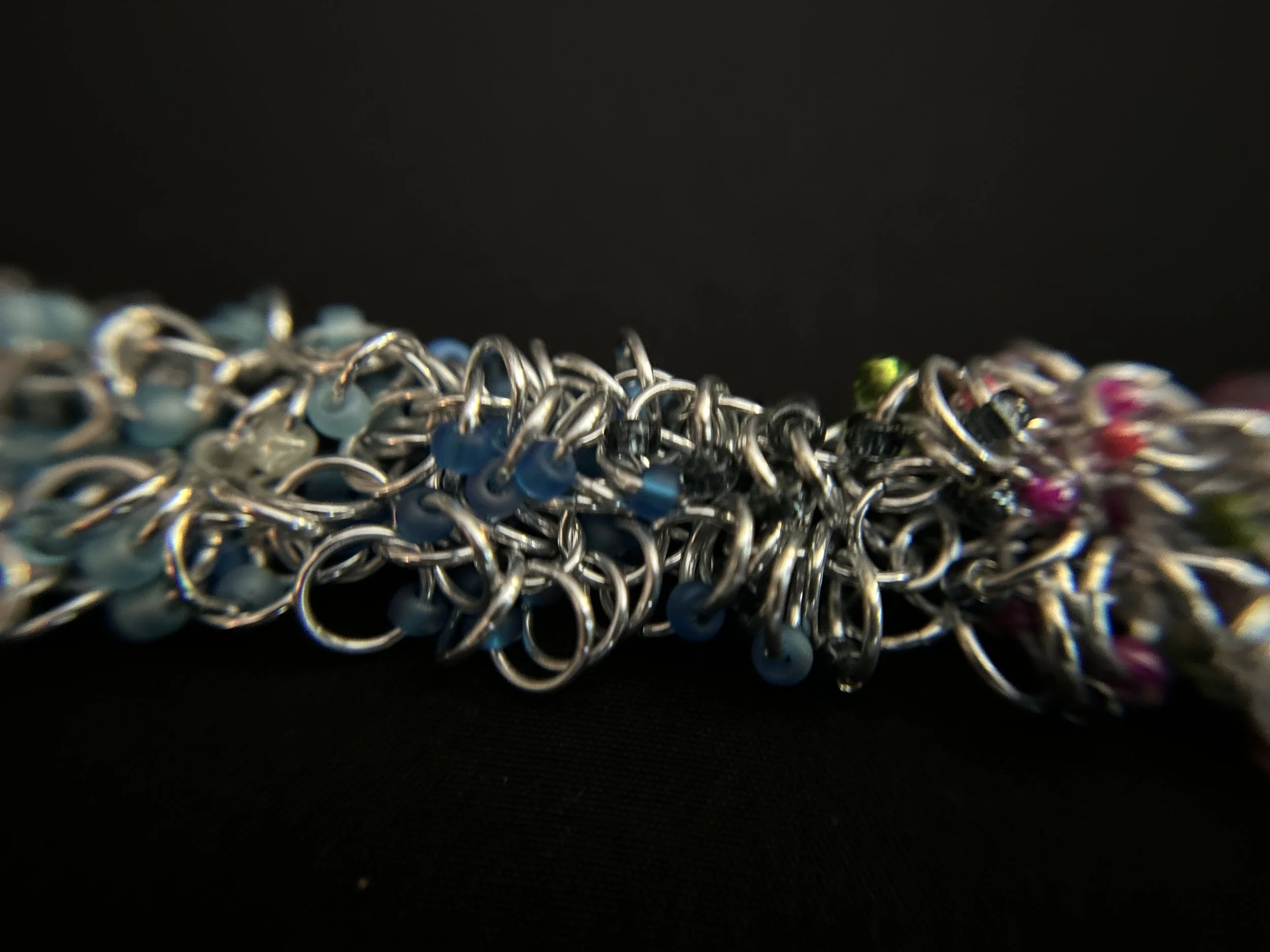 Closeup of the Blue Ridge Spring Bracelet highlighting the detailed chainmaille weave and pink, green, and blue accents.