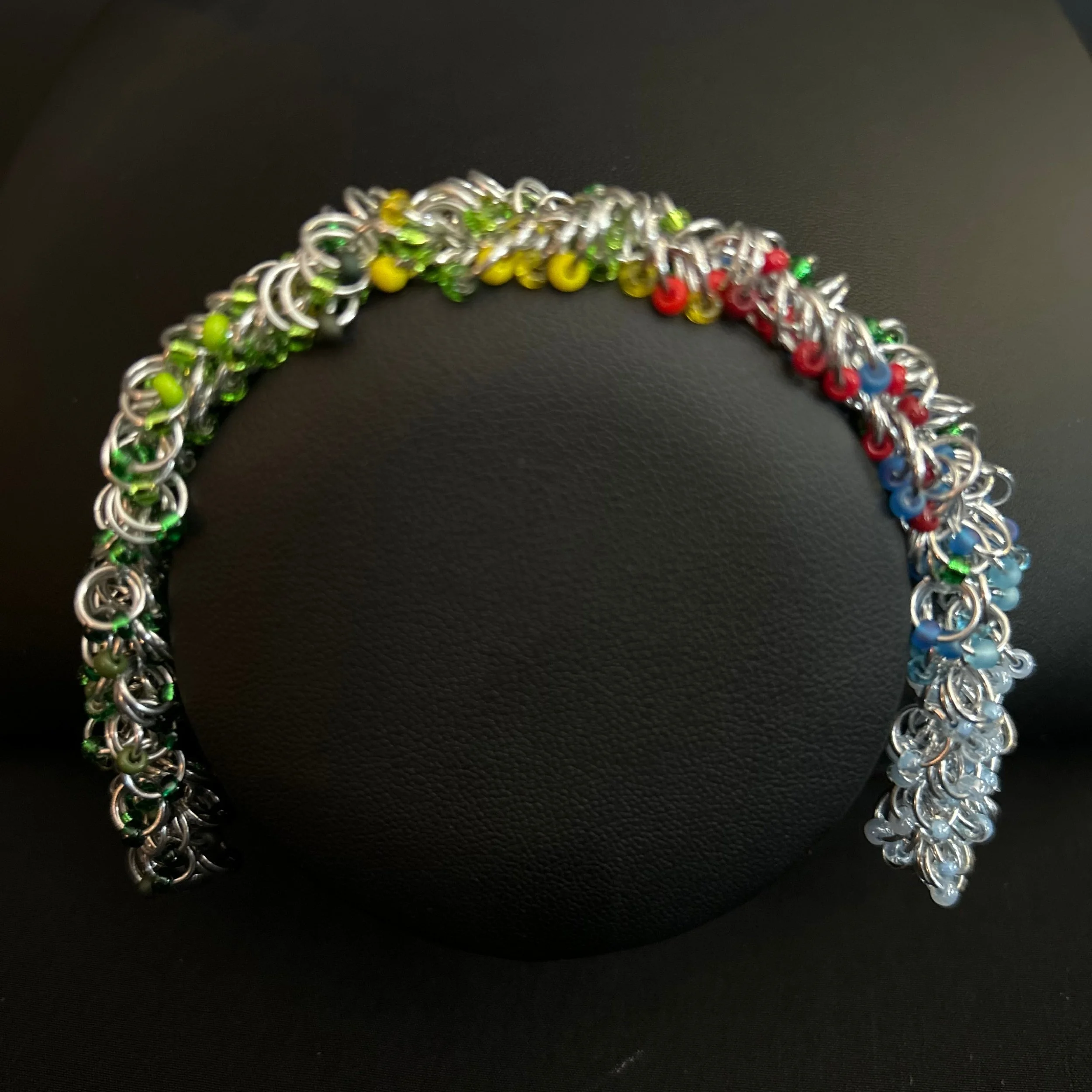 “Summer‑tone chainmaille bracelet displayed on a black jewelry bust.”