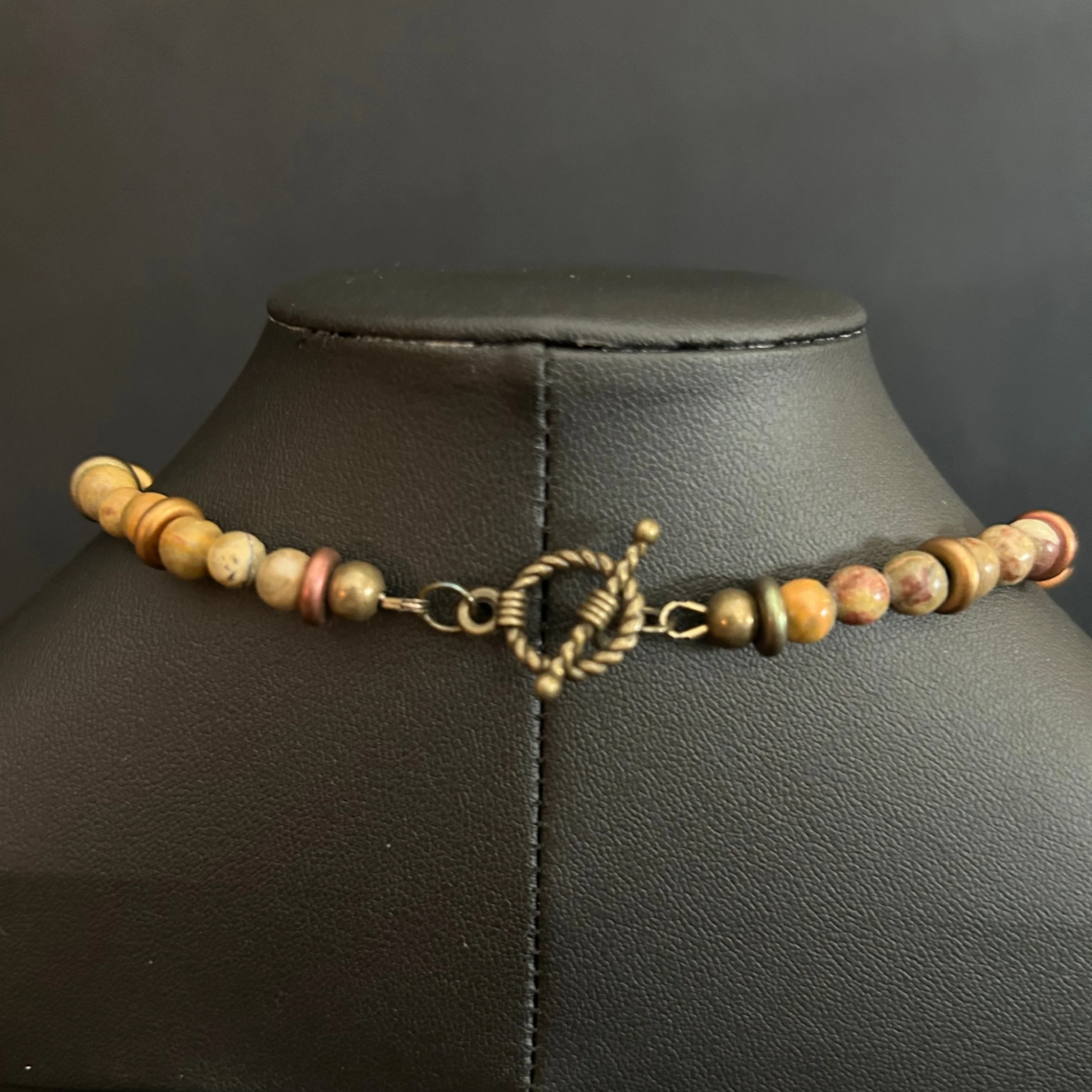 “Close-up of the bronze toggle clasp on the jasper necklace.”