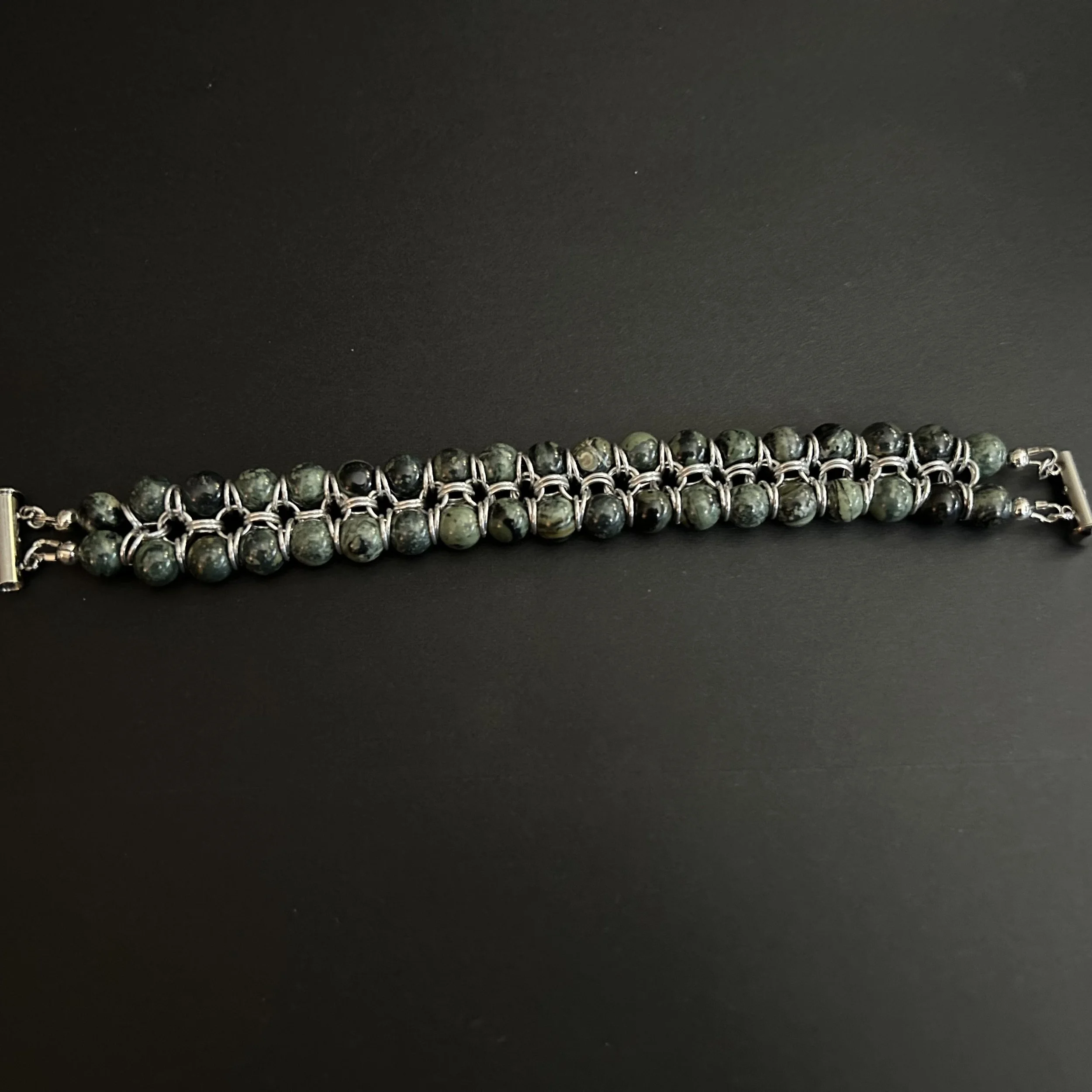Twinstrand bracelet with 8mm Kambaba Jasper beads and silver aluminum rings displayed on a matte black background.