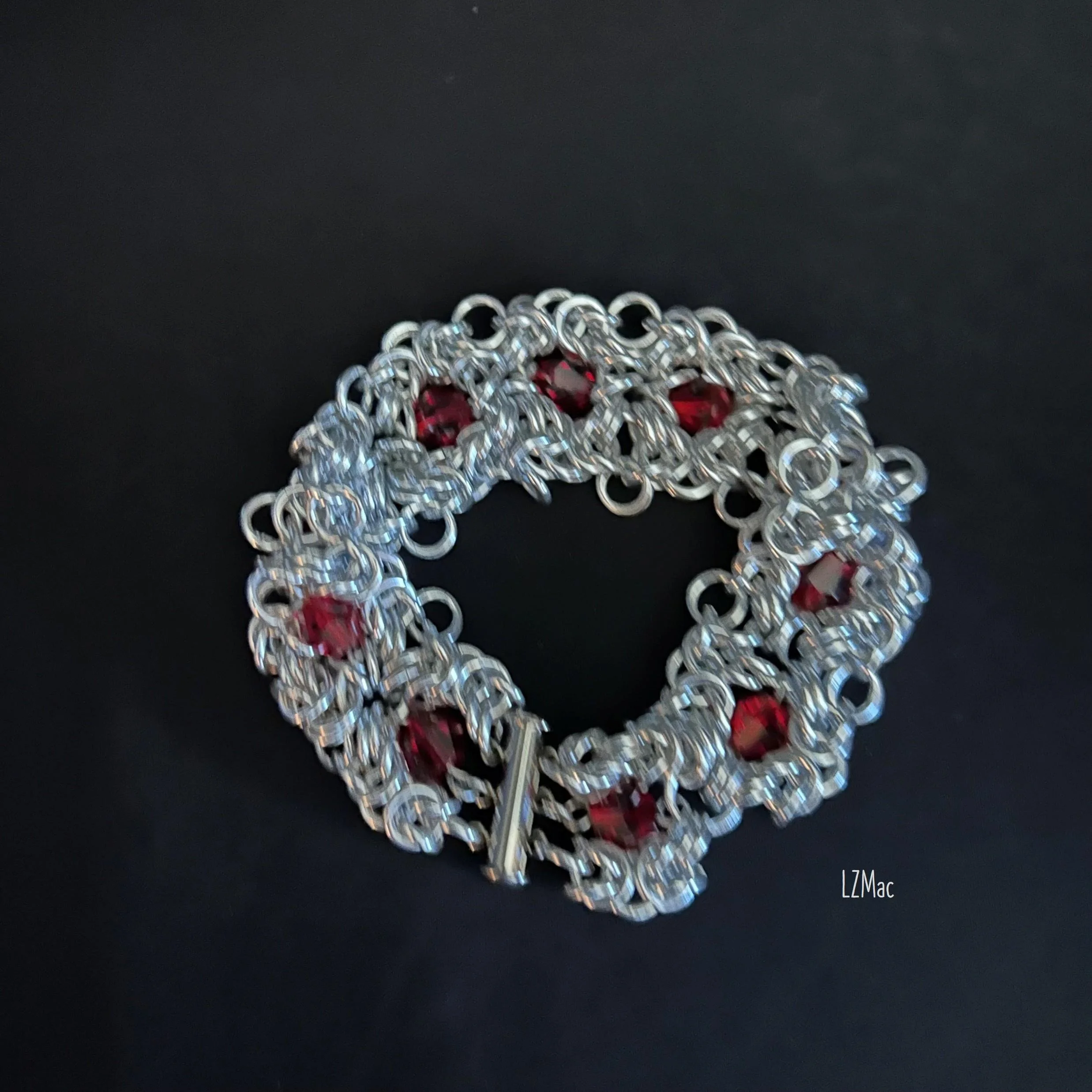 Ruby Frost handcrafted silver chainmaille bracelet with red glass crystals on black background
