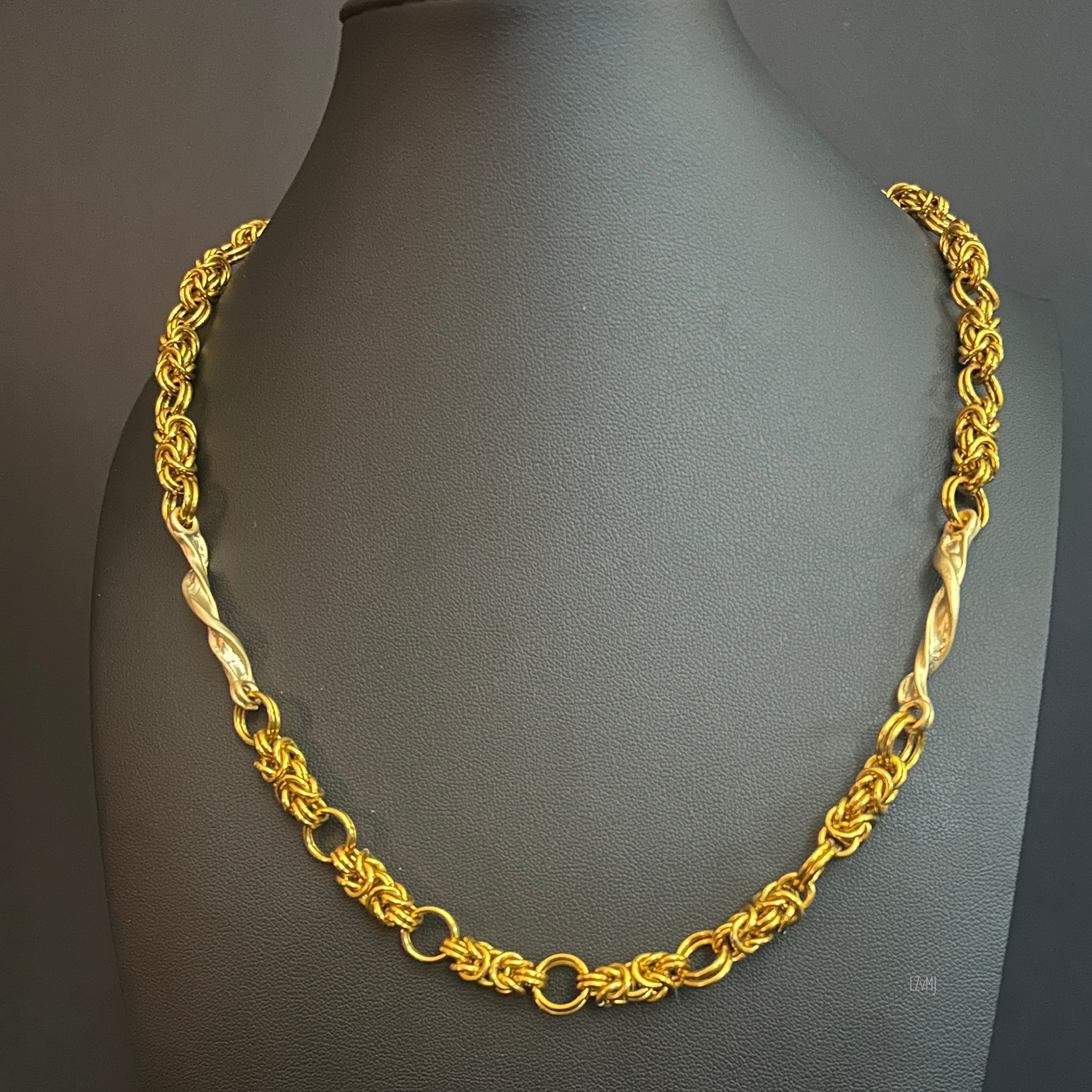 “Twist of Light necklace with gold‑tone aluminum chain and gold‑plated twisters on a black bust.”