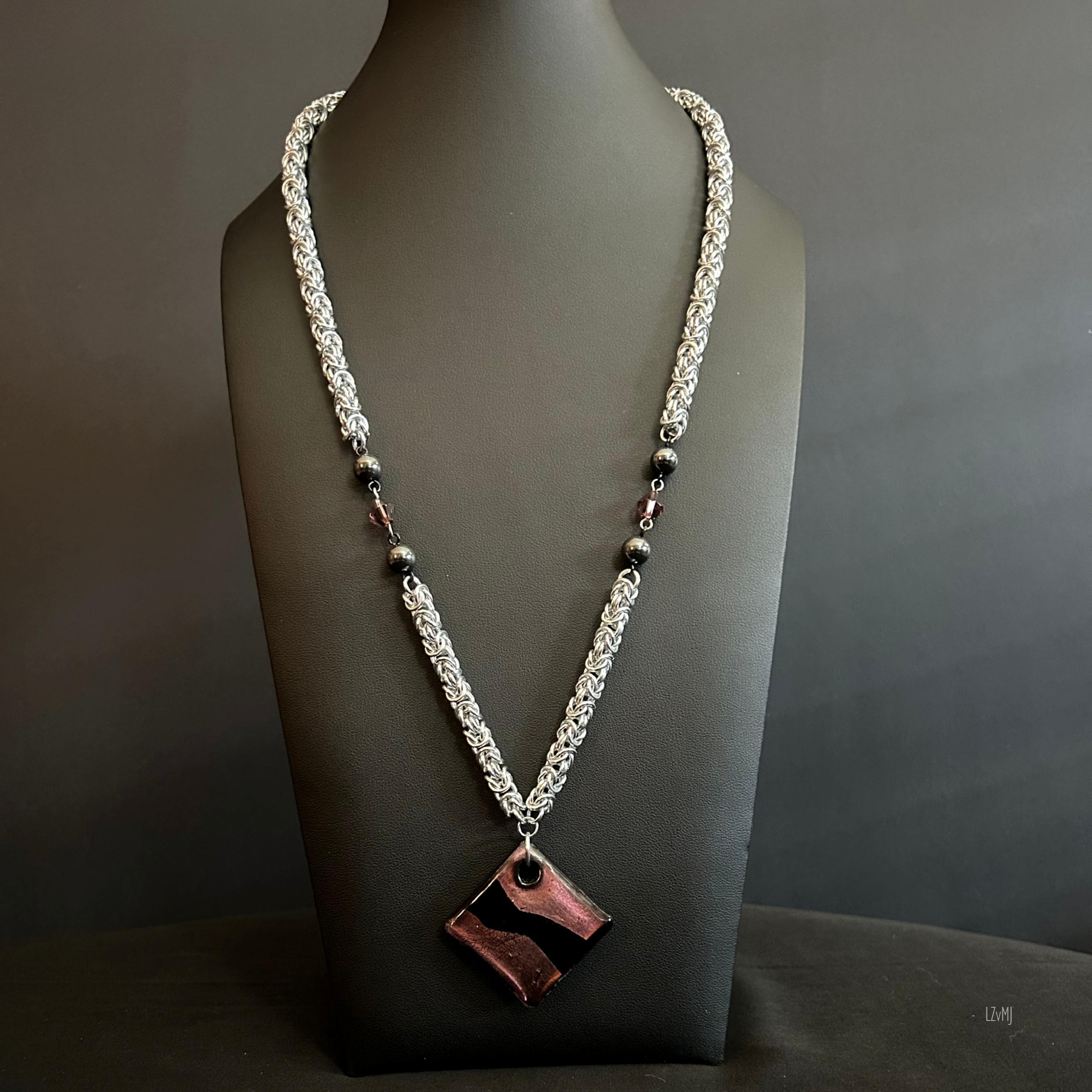 “Full view of the aluminum chain necklace with plum glass focal and hematite and purple beads.”