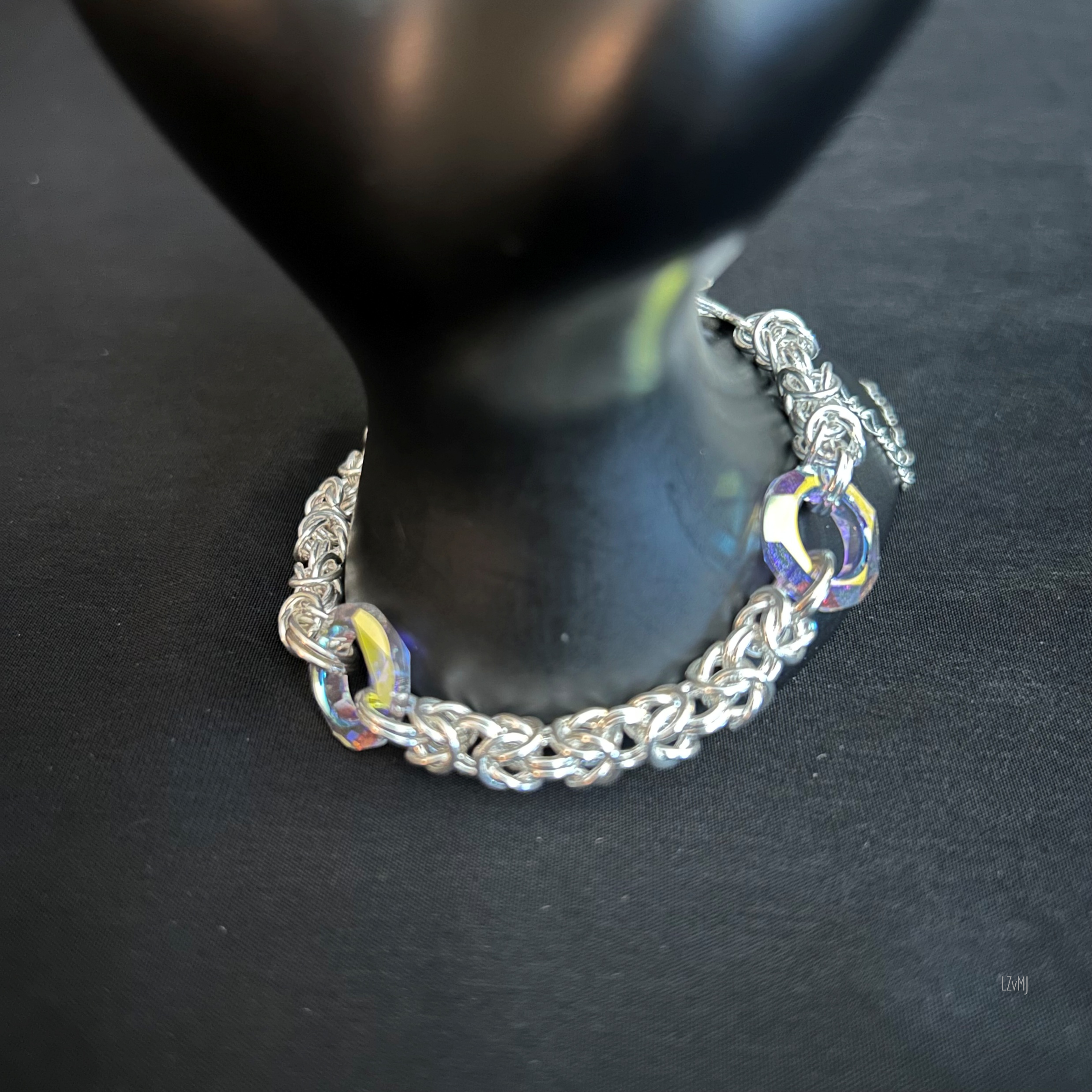 Sterling Byzantine bracelet with yellow and blue‑purple Swarovski donuts styled on a prop to highlight texture and color.