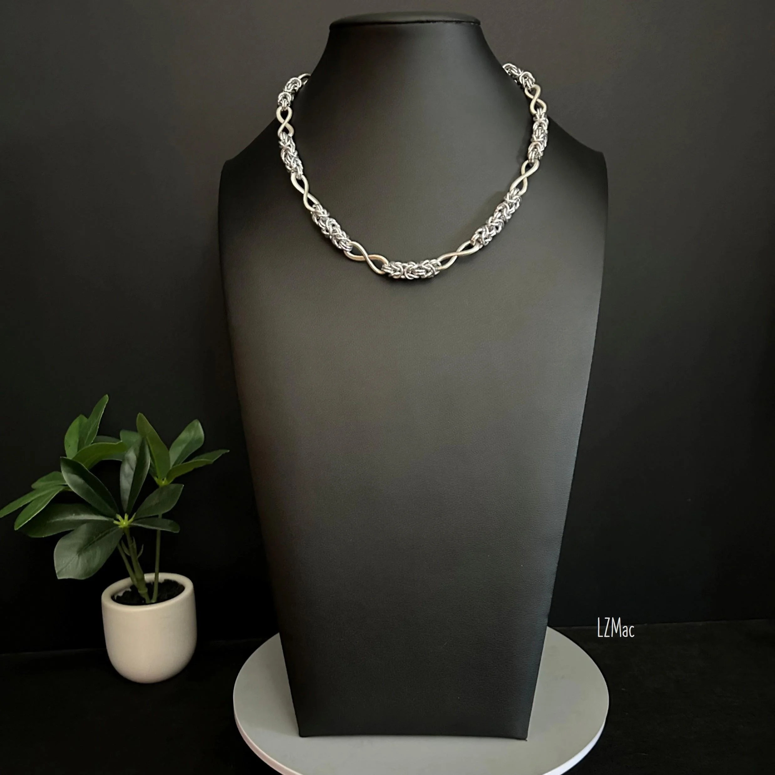 Full-length view of the Silver Infinity necklace showing repeating Byzantine chainmaille segments and infinity connectors with adjustable extender chain.