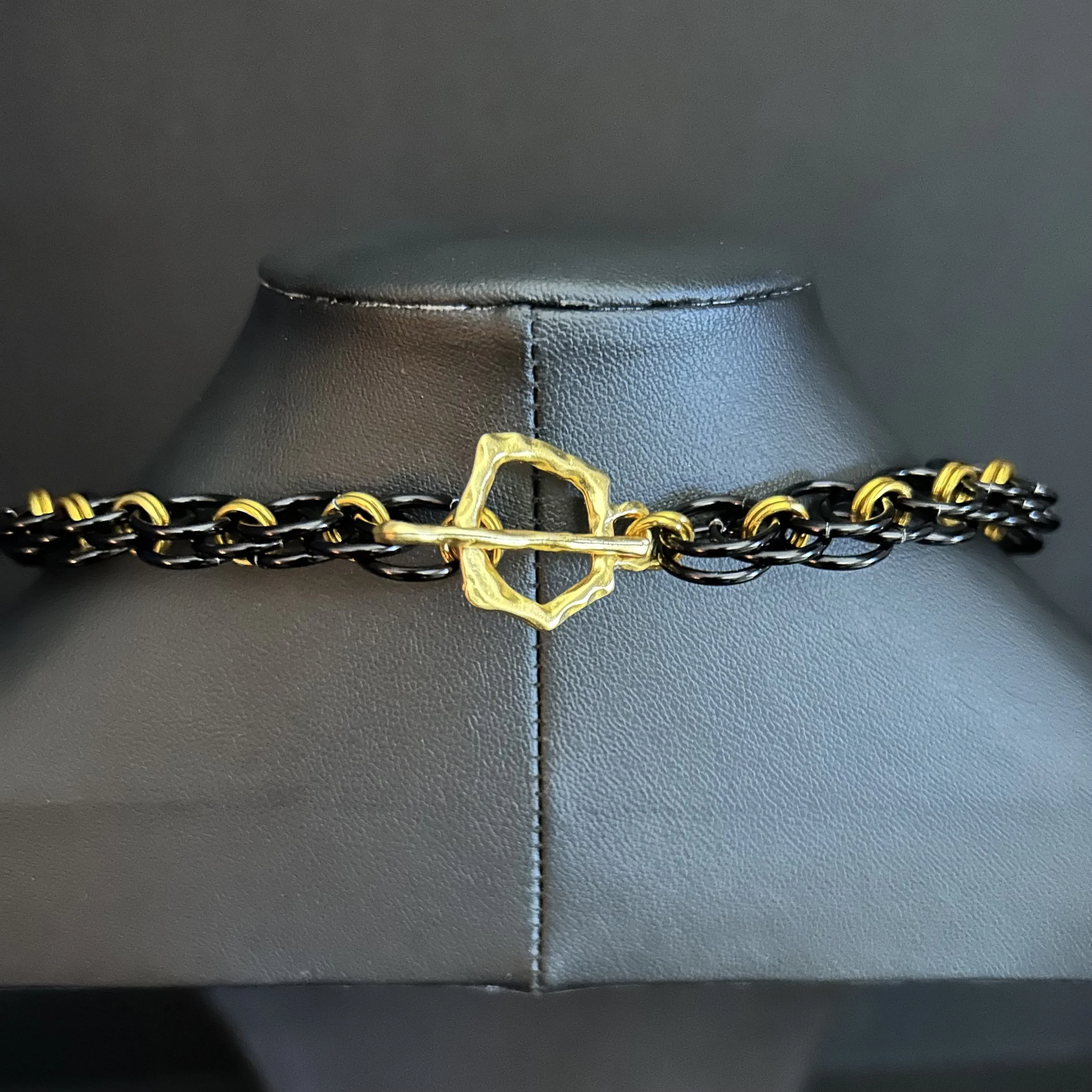 Blackgold Ladder necklace clasp shown on a display bust, highlighting the sculptural toggle closure and contrasting black and gold aluminum rings.