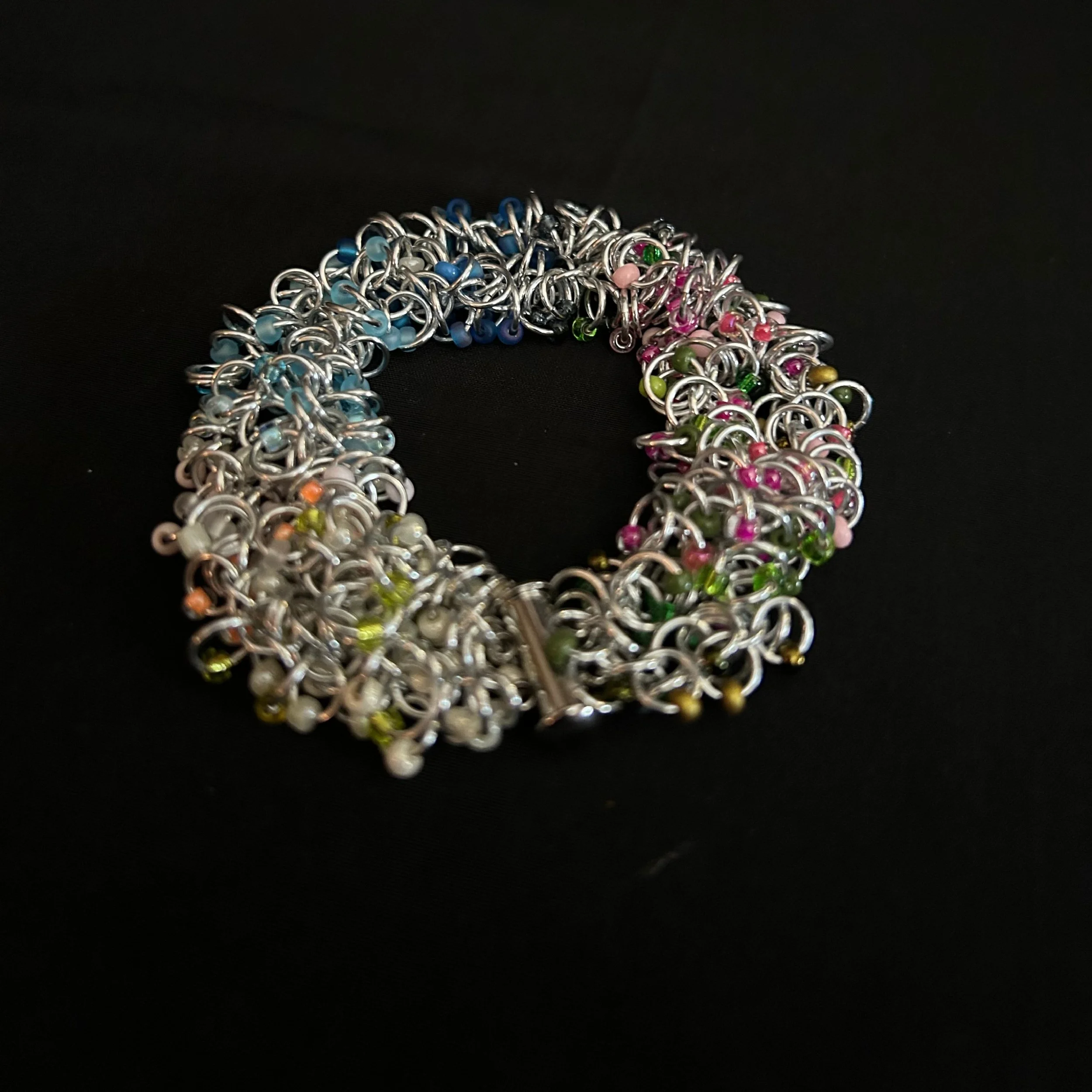 “Blue Ridge Spring bracelet laid flat in a round shape showing aluminum rings and pastel beads.”